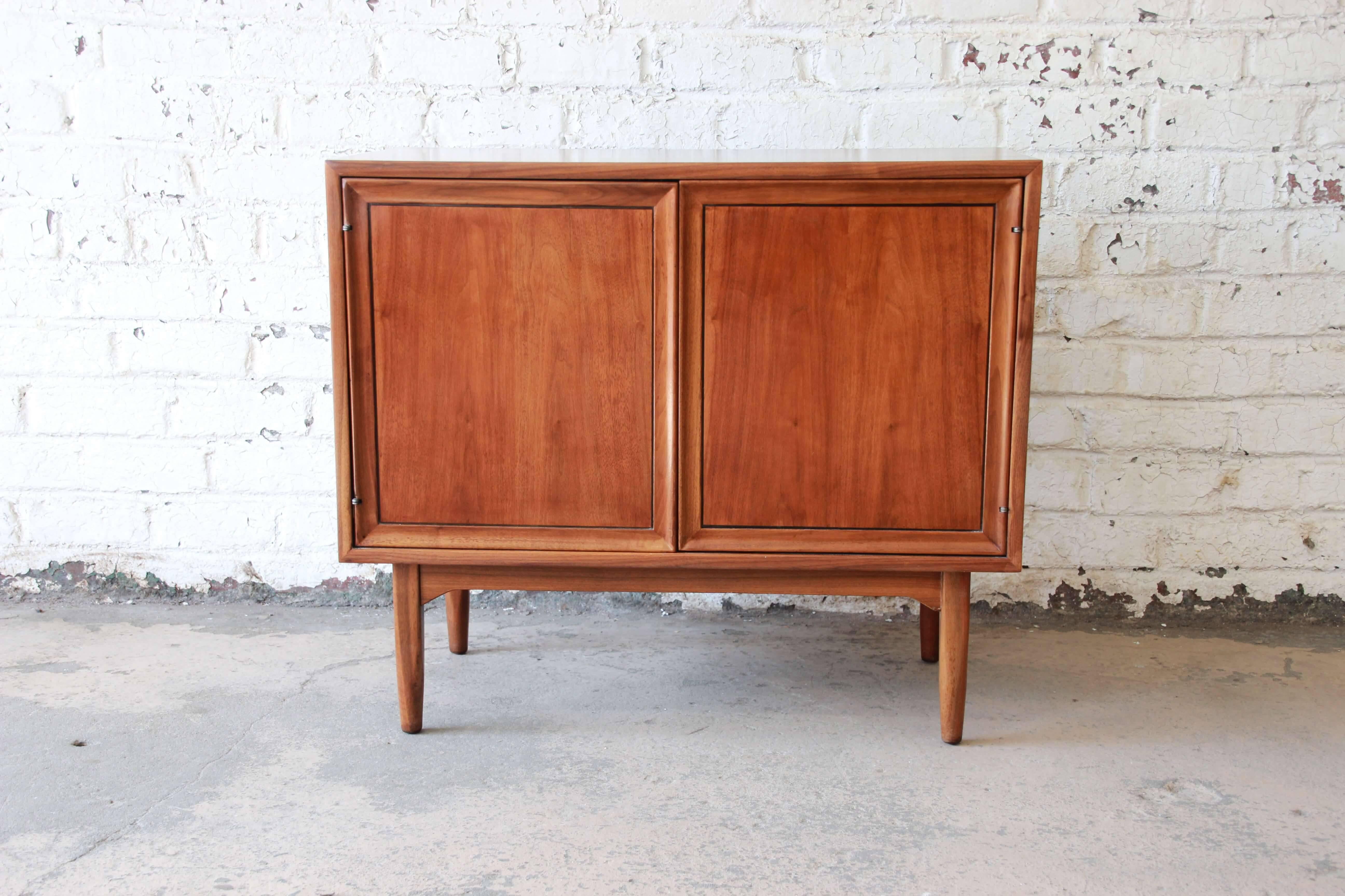 Offering a newly refinished and rare Kipp Stewart for Drexel record cabinet, circa 1963. The cabinet is newly refinished and has a beautiful walnut wood grain. The two cabinet door open up to reveal fourteen record slots and a small shelf area