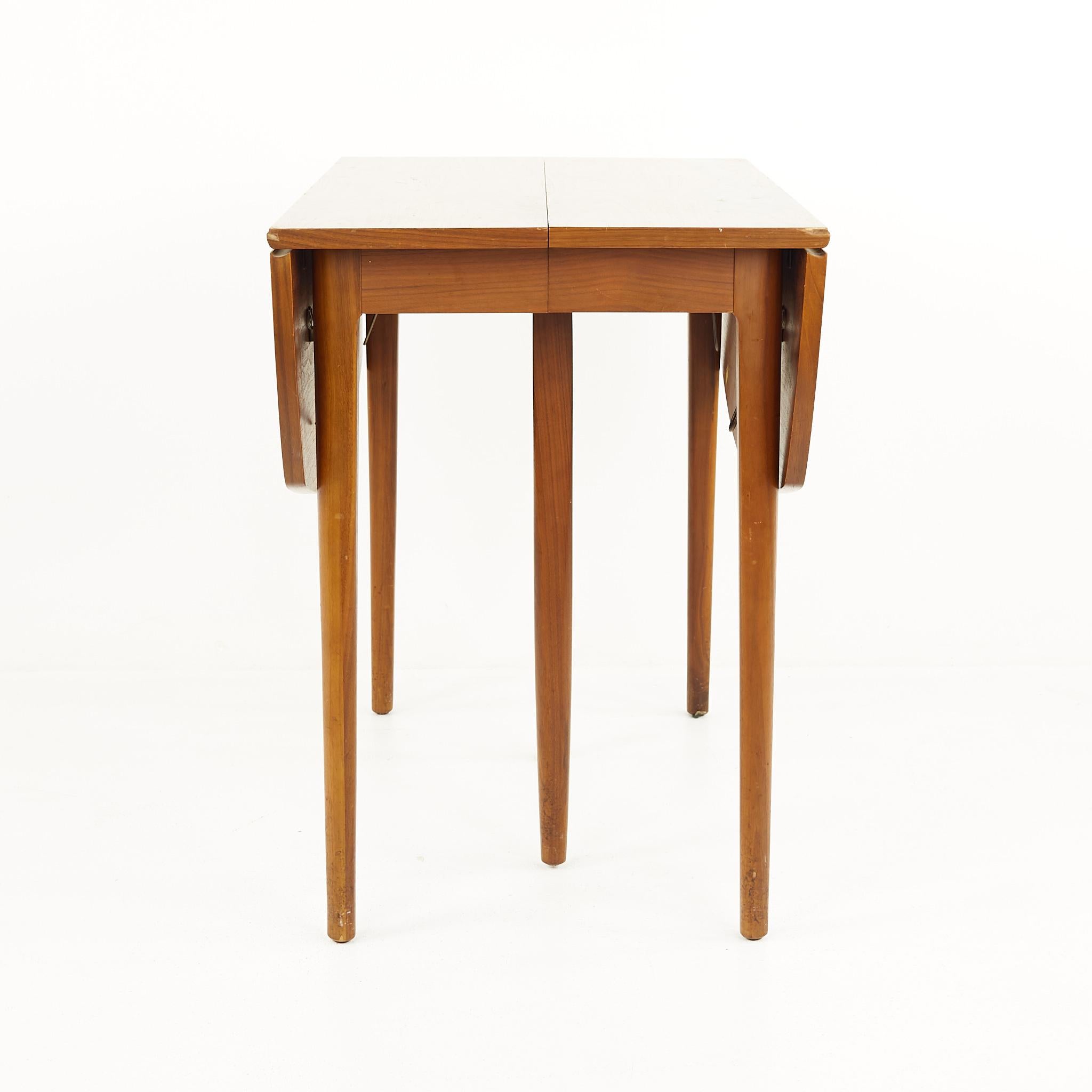 Kipp Stewart for Drexel mid century walnut drop leaf dining table

The closed table measures: 21.5 wide x 38 deep x 29.75 high, with a chair clearance of 28.75 inches

The open table measures: 45.5 wide; each leaf is 13 inches wide, making a