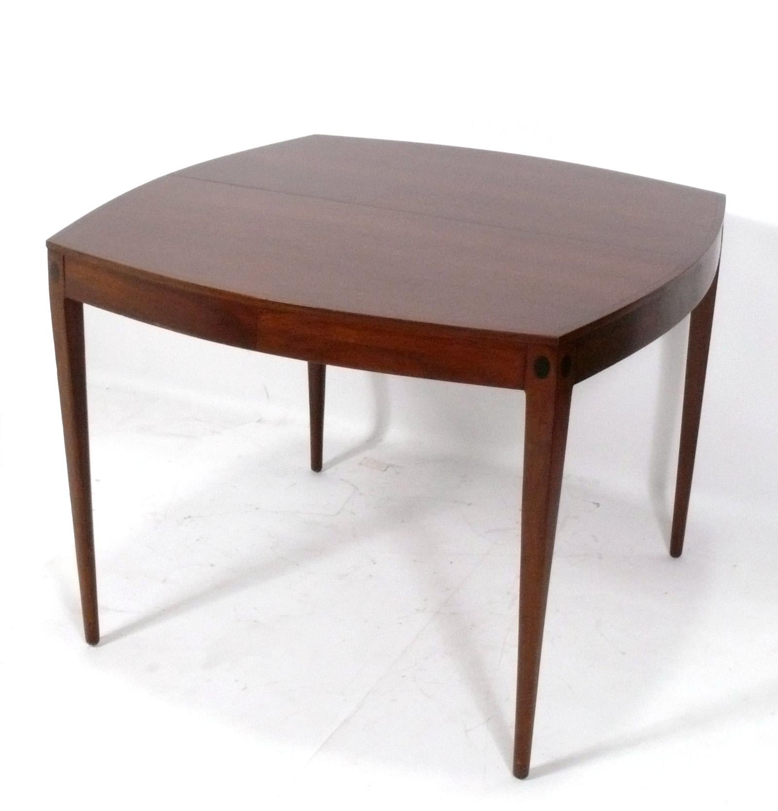 Outstanding midcentury walnut dining table, designed by Kipp Stewart for Directional, American, circa 1960s. Beautiful grained walnut throughout. It expands from a compact ovaled square to an impressive 82.25