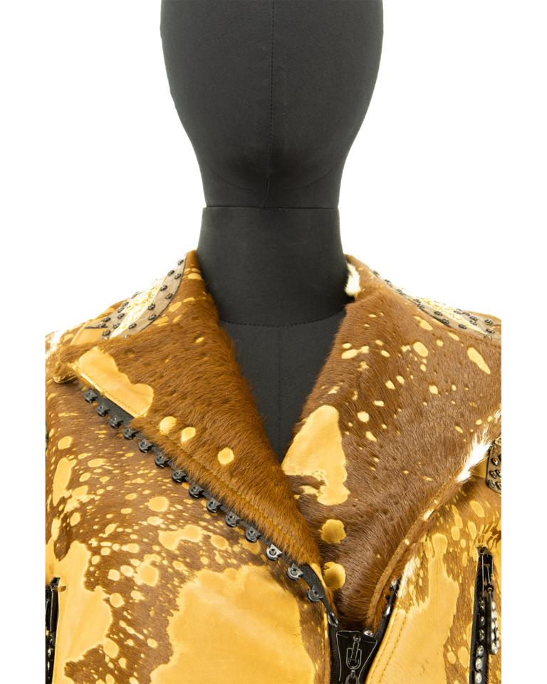 Insolita giacca di ispirazione western di Kippys of Coronado, realizzata in pelle di mucca con un'applicazione di pelli animali a contrasto, impreziosita da strass e smeraldi finti. Questa giacca è una rivisitazione di un look in stile rodeo che