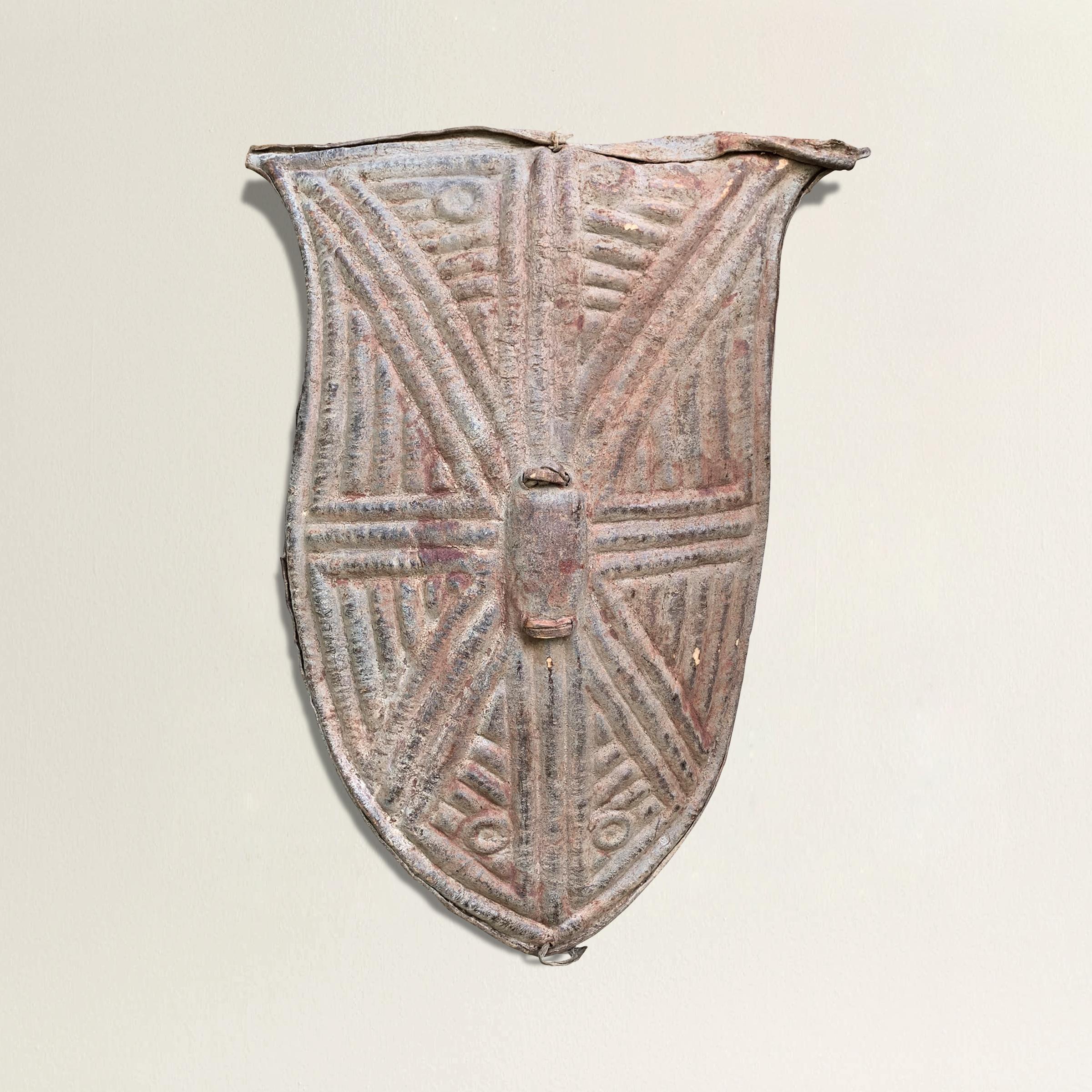 A wonderfully sculptural Kirdi leather shield from Cameroon, with a beautiful geometric pattern that's been 'stamped' into the leather resulting a raised surface on the face of the shield. We've had a custom steel mount made so that the piece can