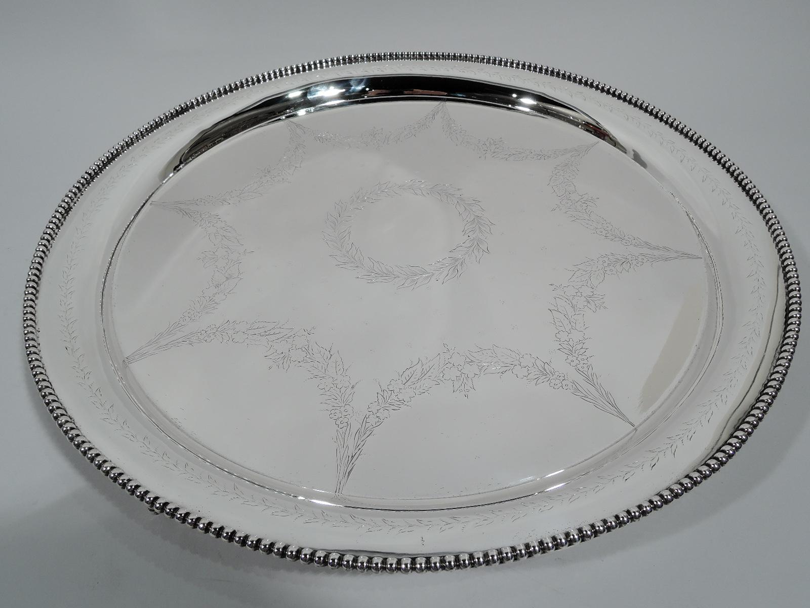 Edwardian sterling silver salver. Made by S. Kirk & Son Co. in Baltimore. Round with boldly beaded rim. Well engraved with central laurel wreath (vacant) and ornamented ground framed by pendant laurel wreaths. Georgian form and Regency Revival