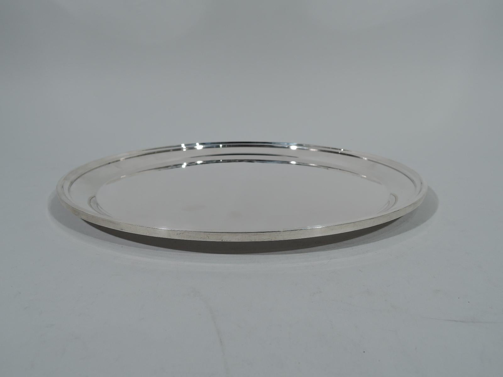 Plain and practical sterling silver serving tray. Made by S. Kirk & Son in Baltimore. Circular with tapering sides and molded rim. Hallmark (1932-61) and no. 4112. Weight: 23 troy ounces.