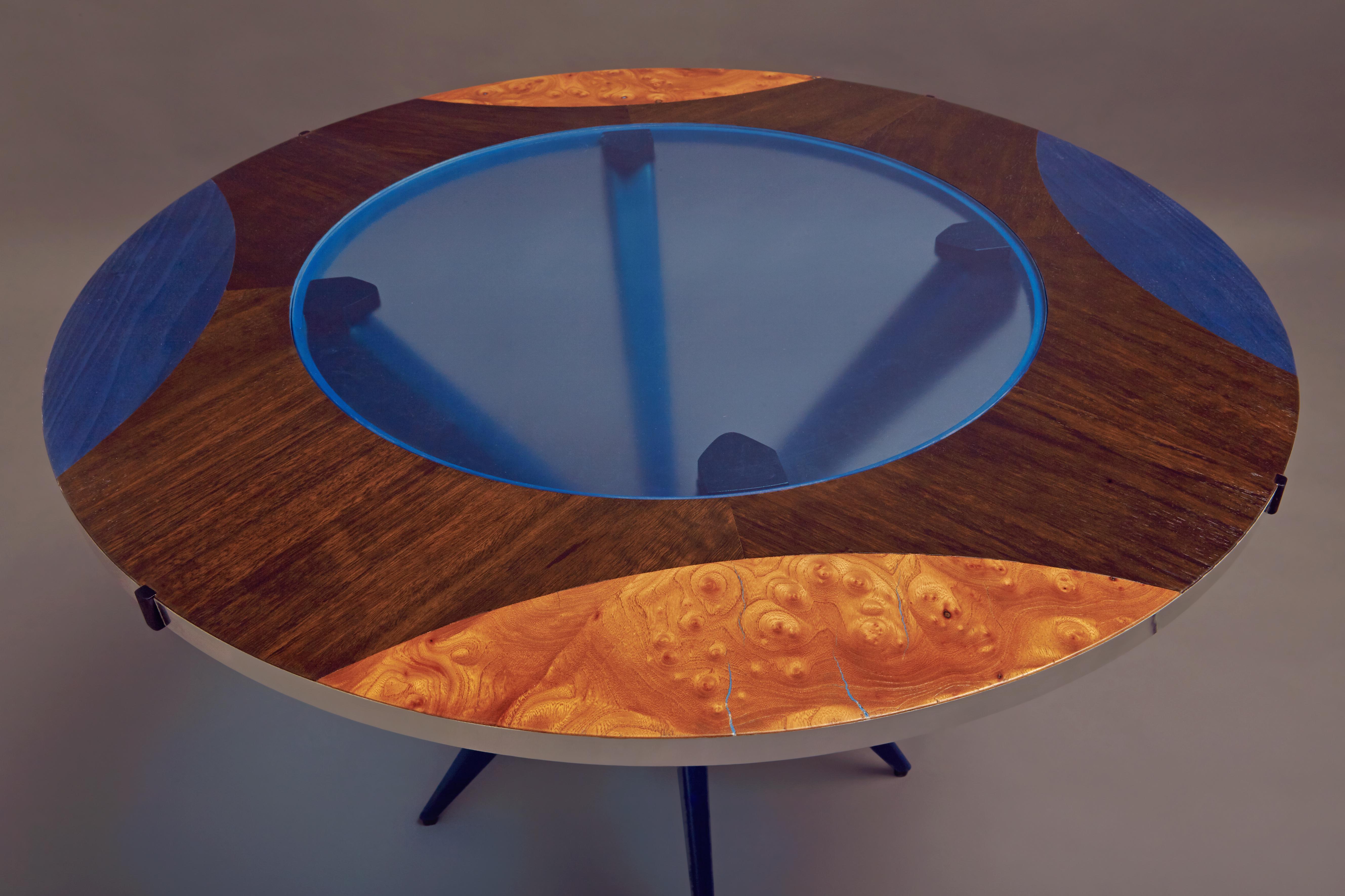 Cocktail table in veneered smoked eucalyptus with dyed blue inlays mixed with olive radica, light blue glass. Aluminum ring.
The base is in solid hand painted blue


Suprematism is an art movement focused on basic geometric forms, such as