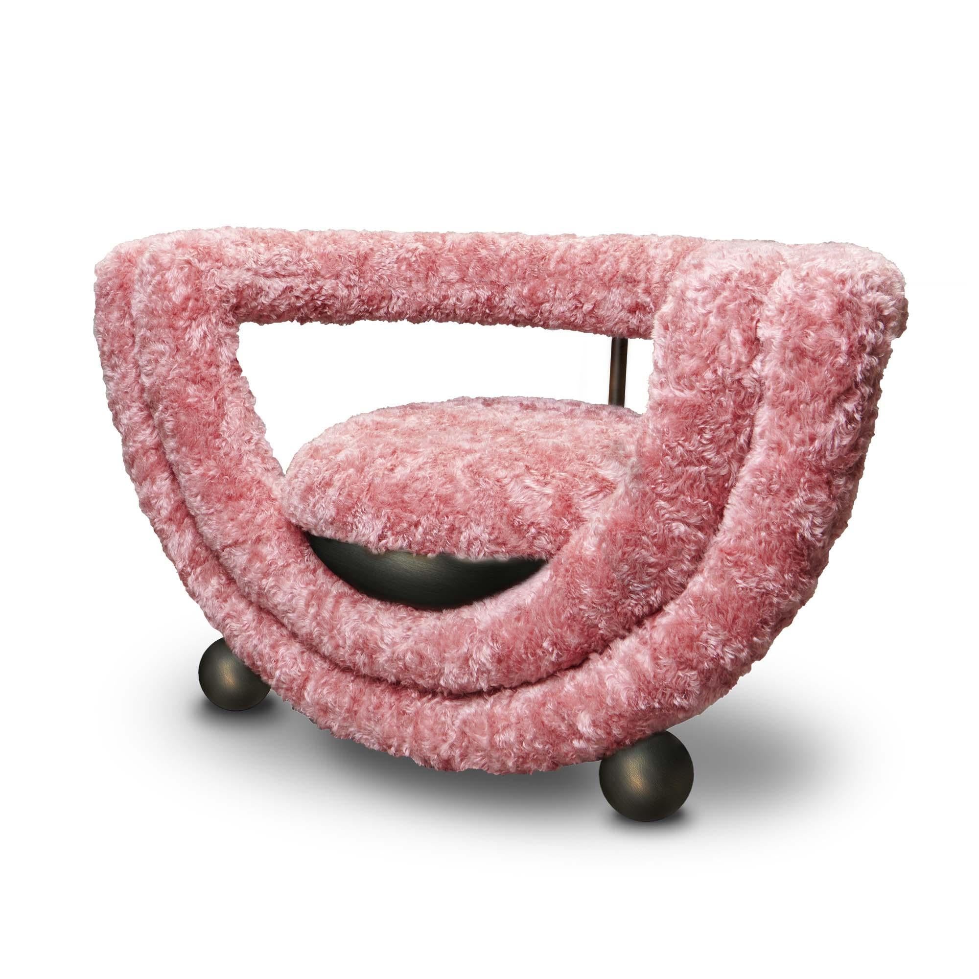 Kissing armchair features two semi-circle layers; one bearing the cupped seat and a second forming the back-rest. All the lines are covered with soft upholstery apart from the metal legs, which hold the upholstered seat like an ice cream coupe. It