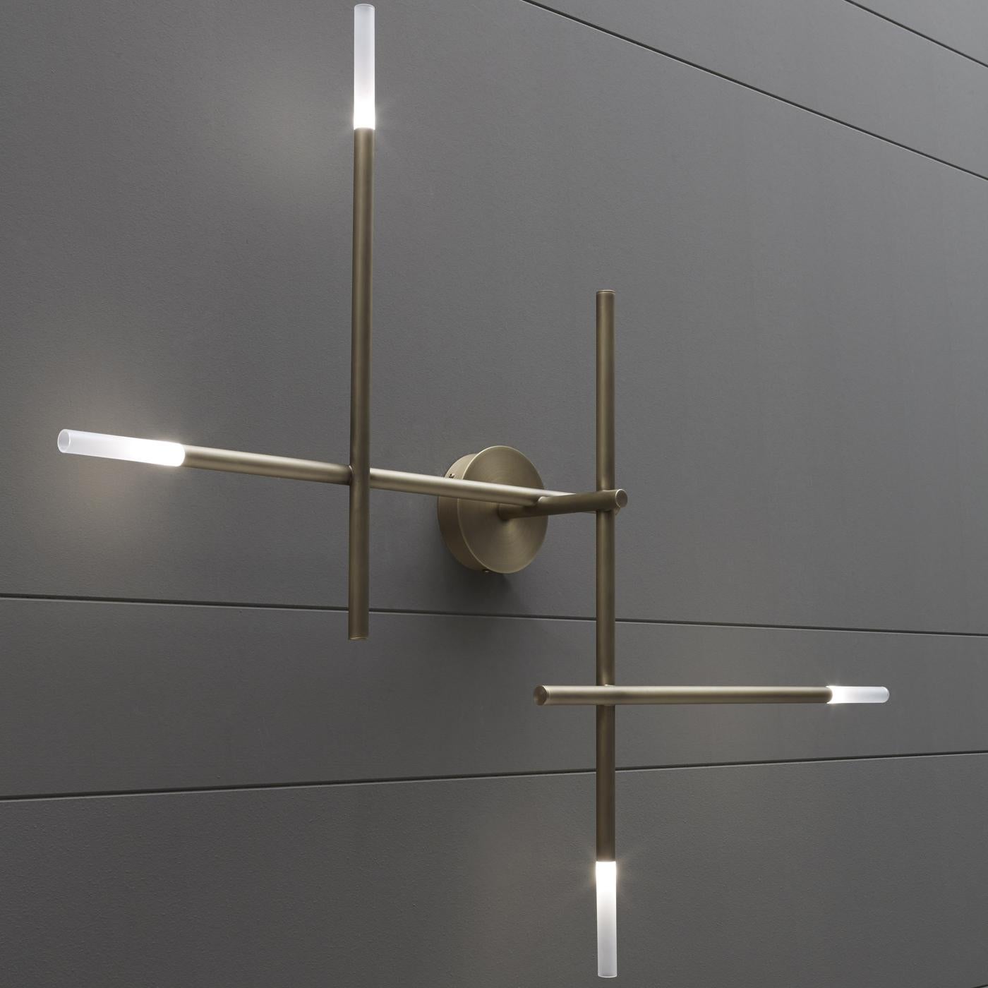 This elegant wall lamp projects direct light from glazed glass diffusers mounted at the top of metal rods assembled to form a system of parallel and perpendicular lines. The finish of the metal can be in striped dark bronze, etched bronze, polished