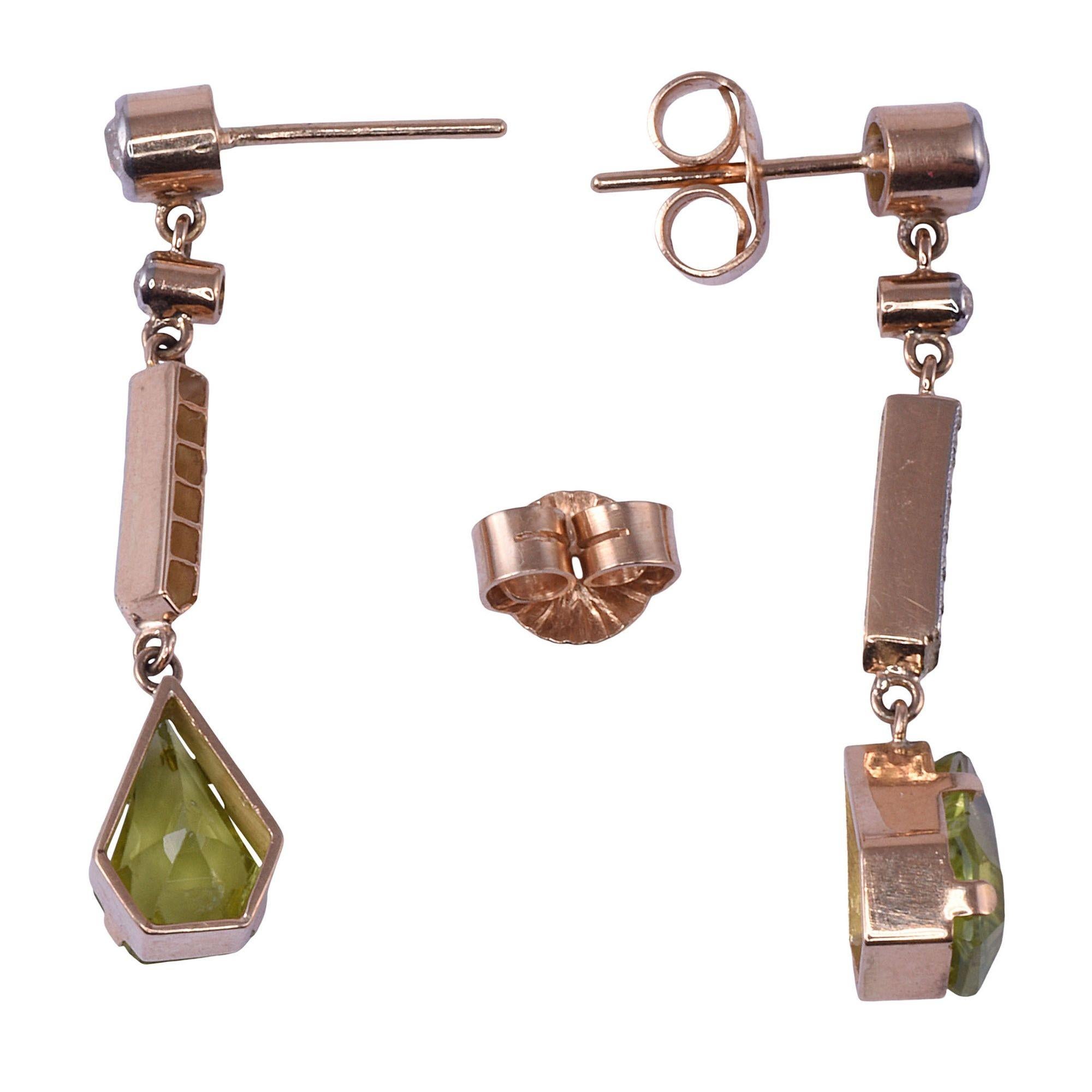 Vintage kite shaped peridot earrings. These 14 karat gold dangle earrings feature kite shaped peridot at 2.90 carat total weight accented with .37 carat total weight of diamonds. The diamonds have VS-SI clarity and H-J color. Please note: these