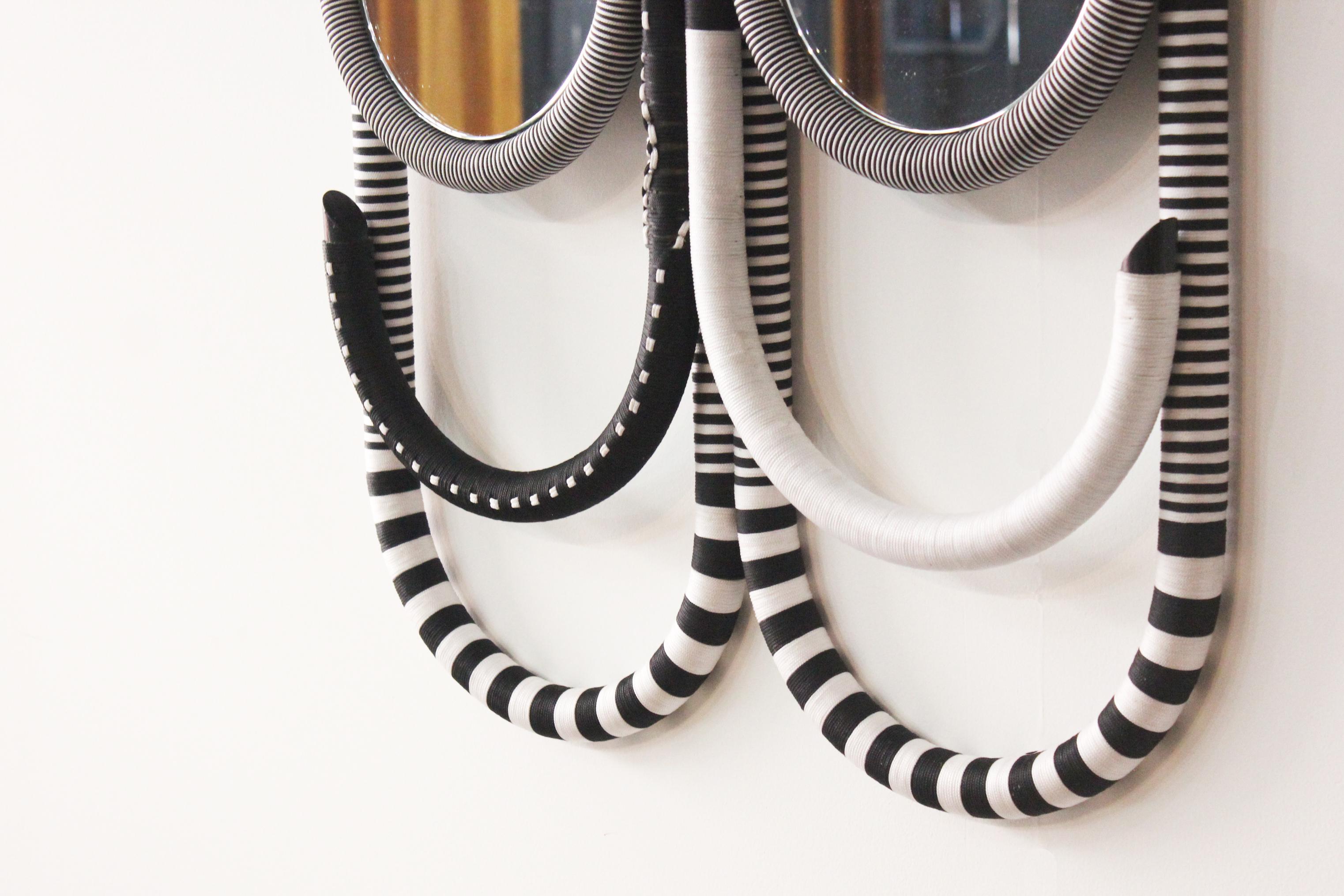 The Kitt mirror is a simplified translation of symbolic tribal visual language. The hand-curved rattan base is overworked with cording techniques in contrasting black and white to reflect African tribal bead accessories.