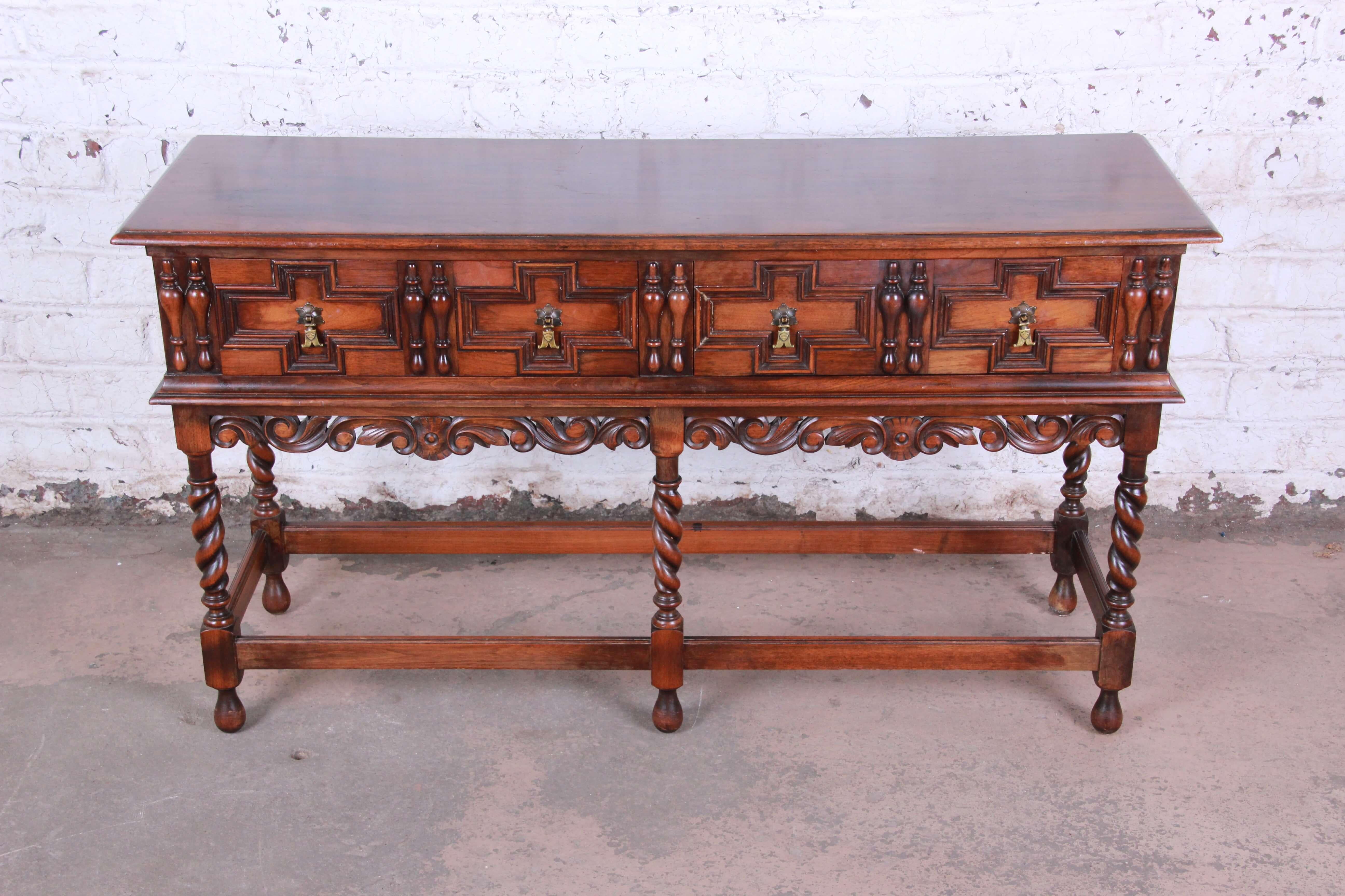 Offering a very nice antique Kittinger carved walnut sideboard buffet or bar server. The piece has detailed ornate carvings with English barley twist legs. There are two large drawers with interiors being solid oak which open and close smoothly. The