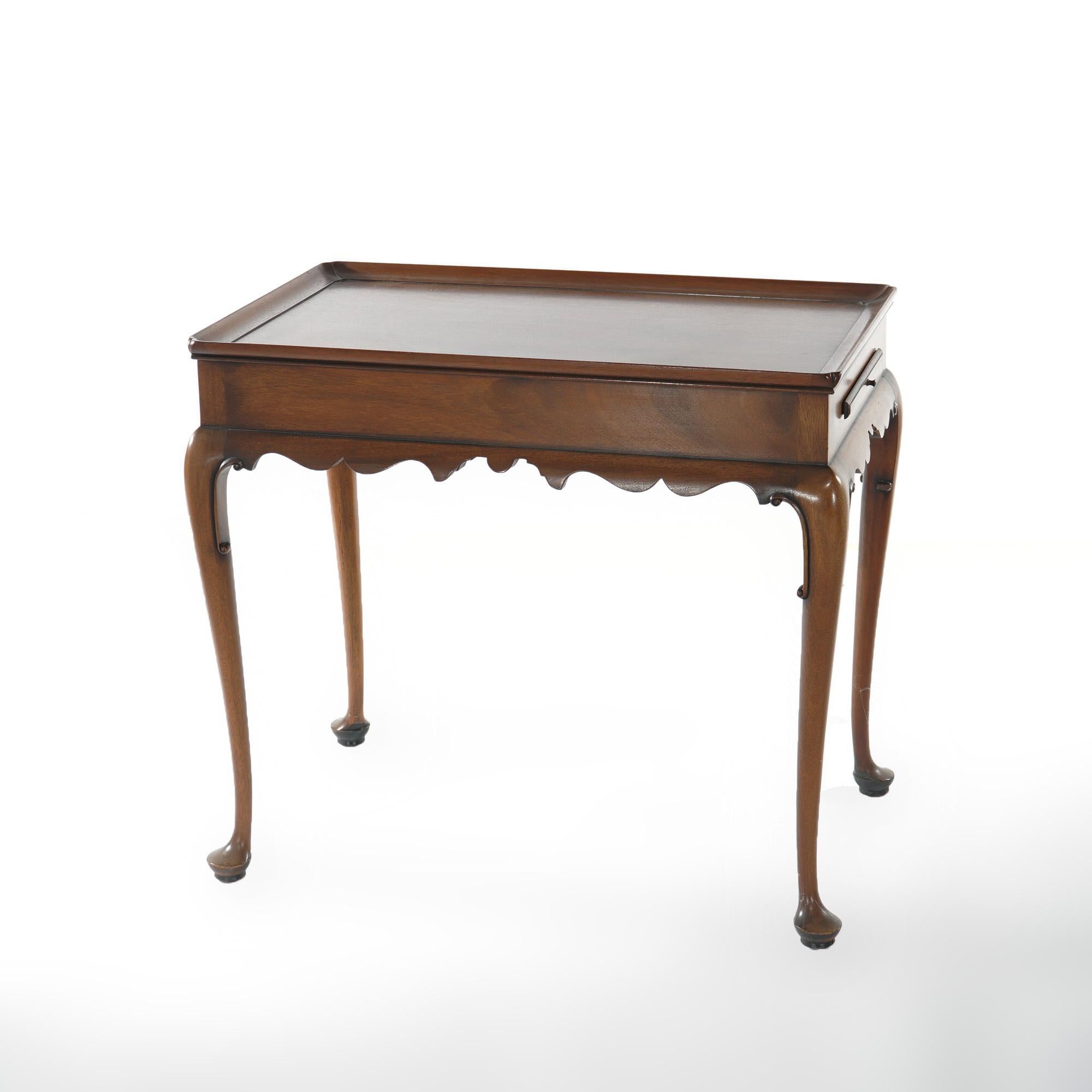 A side tea table by Kittinger of the Colonial Williamsburg collection offers top with raised lip over base having shaped apron, flanking candle slides and raised on cabriole legs terminating in pad feet; maker mark as photographed; 20th