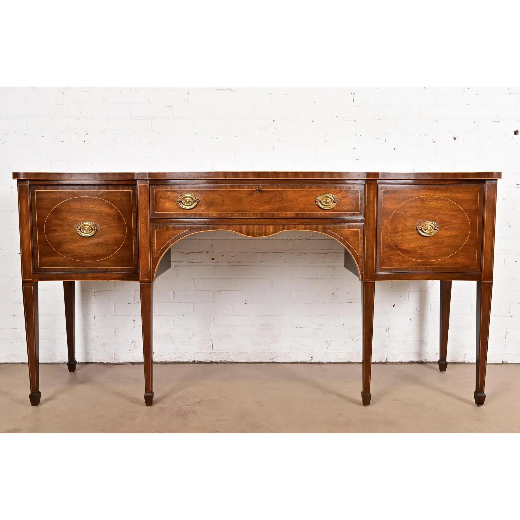 A gorgeous Federal or Hepplewhite style serpentine front sideboard buffet or credenza

By Kittinger

USA, Circa 1980s

Carved mahogany, with satinwood inlay, and original brass hardware.

Measures: 79