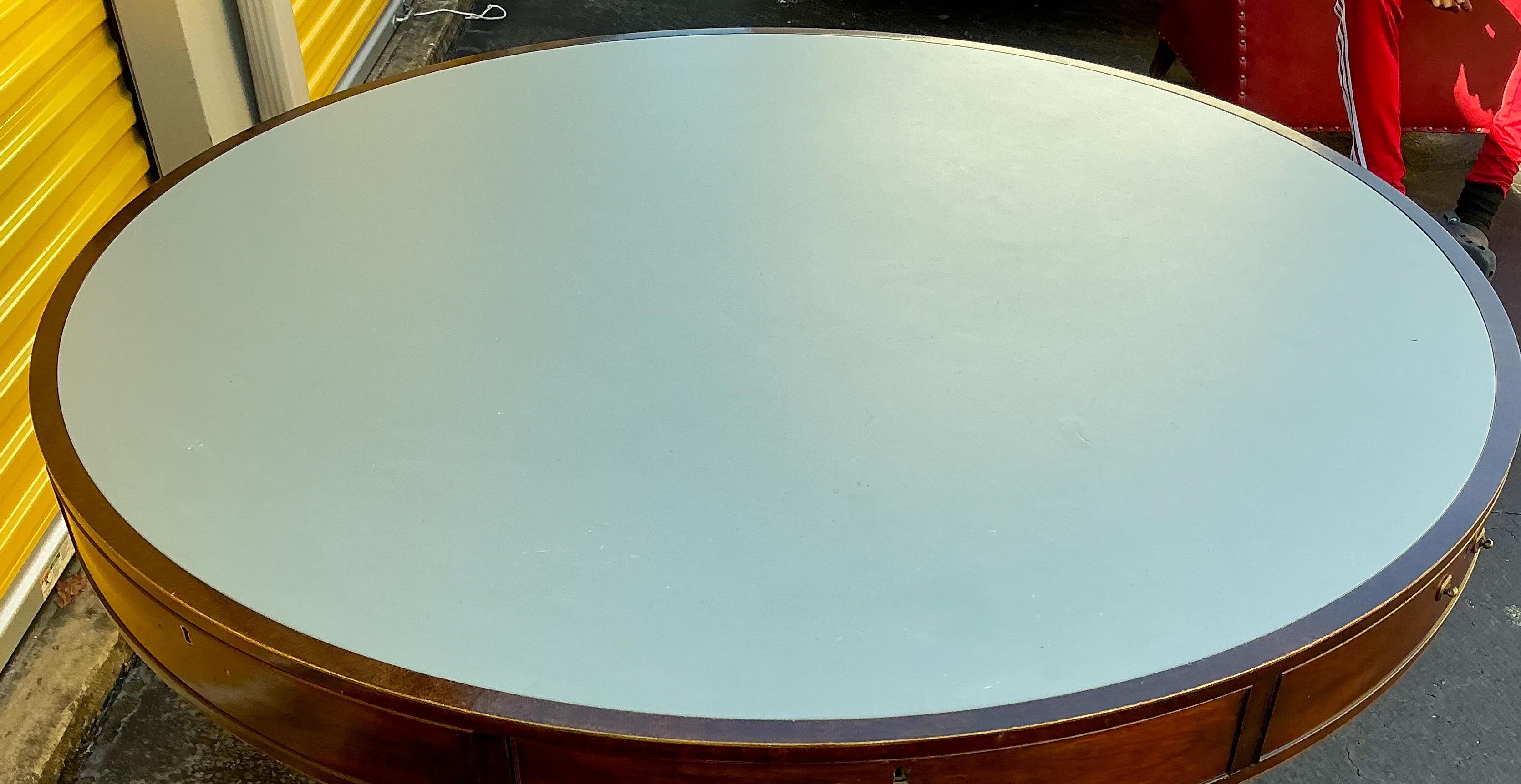 This is a large scale Federal style carved mahogany round rent table with French blue leather top by Kittinger. I believe this to be a custom piece for them because of the beautiful blue leather top. It has 7 drawers, but only two are functional.