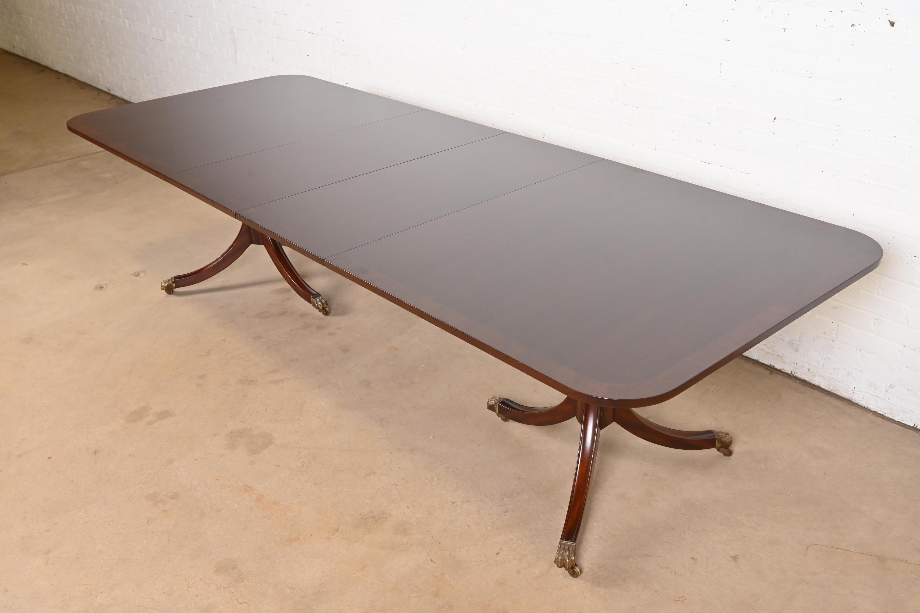 A gorgeous Georgian or Regency style double pedestal extension dining table

By Kittinger

USA, Circa 1980s

Gorgeous banded mahogany top, with carved solid mahogany pedestals, and brass-capped paw feet on brass casters.

Measures: 78