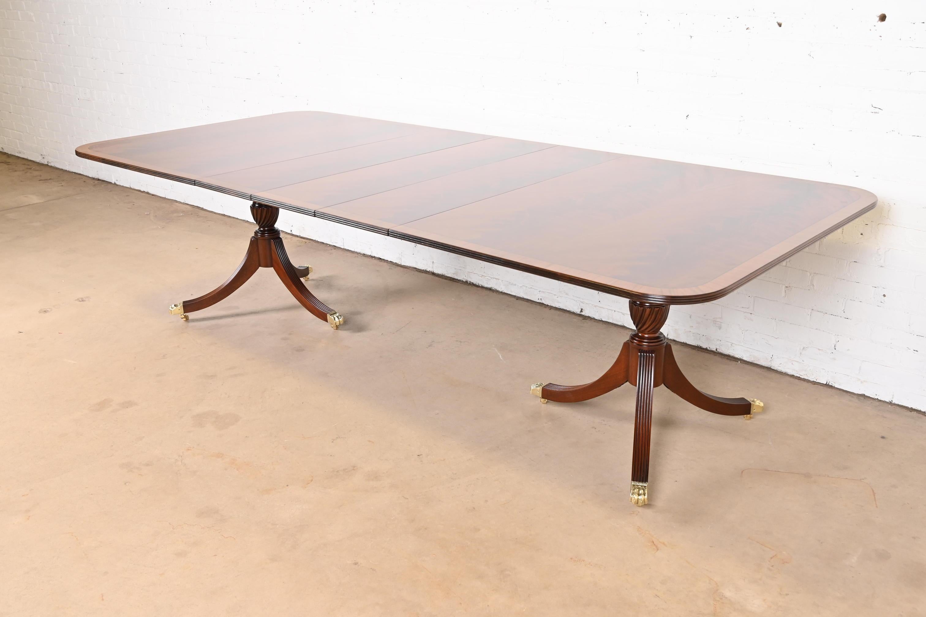 A gorgeous Georgian or Regency style double pedestal extension dining table

By Kittinger

USA, Circa 1980s

Beautiful book-matched flame mahogany with satinwood banding, carved solid mahogany pedestals, and brass-capped paw feet on brass