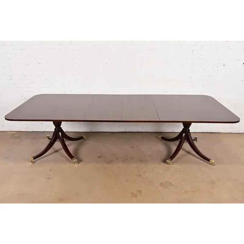 An exceptional Georgian or Regency style double pedestal extension dining table

By Kittinger

USA, Circa 1980s

Gorgeous banded mahogany top, with carved solid mahogany pedestals, and brass-capped feet on brass casters.

Measures: 78