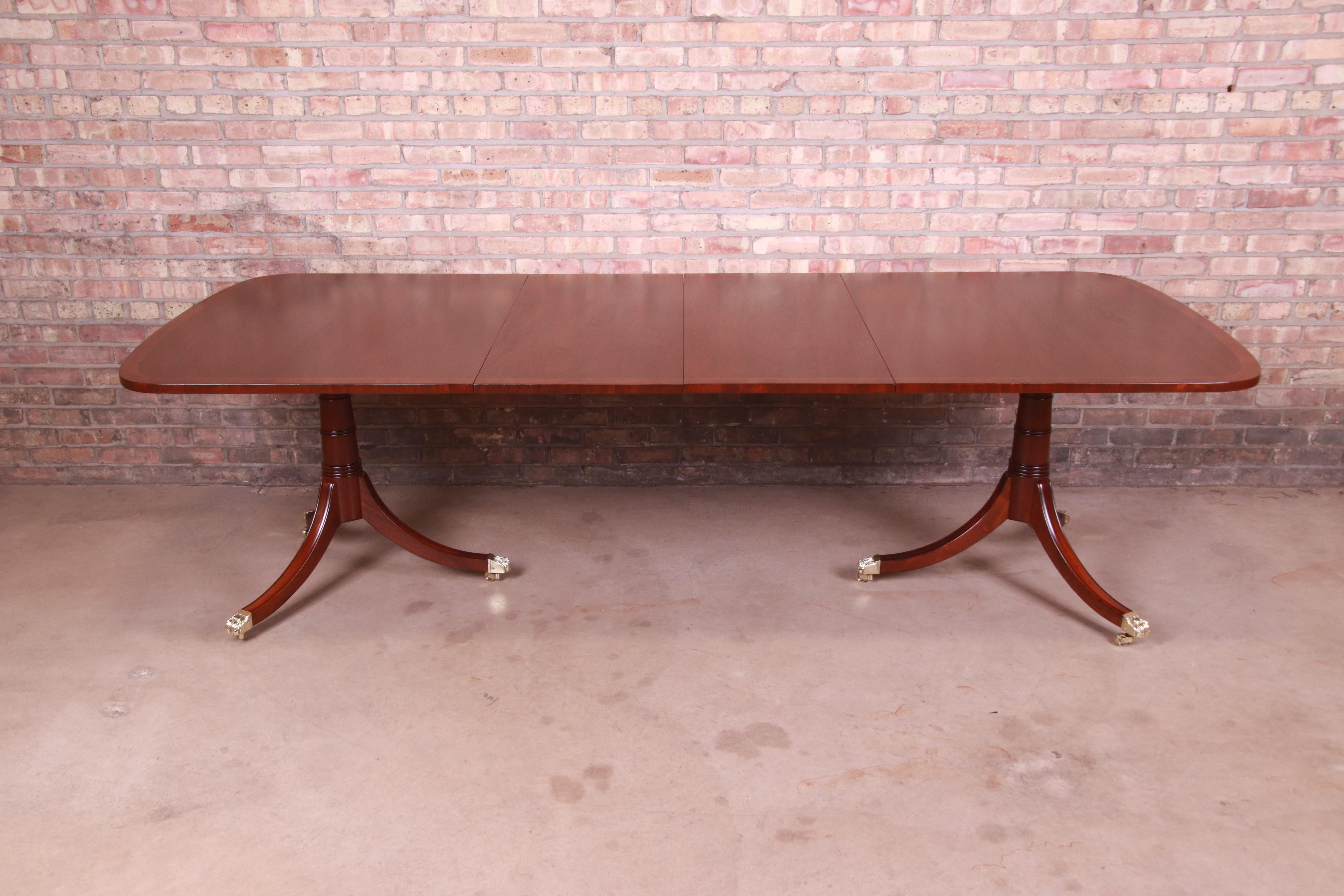 A gorgeous Georgian style double pedestal extension dining table

By Kittinger

USA, Circa 1960s

Banded mahogany, with carved solid mahogany legs and brass-capped paw feet.

Measures: 68