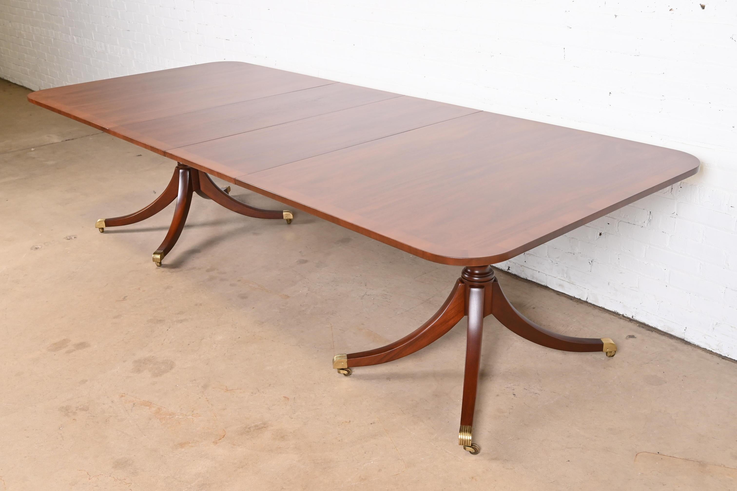 An exceptional Georgian or Regency style double pedestal extension dining table

By Kittinger

USA, Circa 1980s

Gorgeous banded mahogany, with carved solid mahogany pedestals, brass-capped feet, and brass casters.

Measures: 78.25