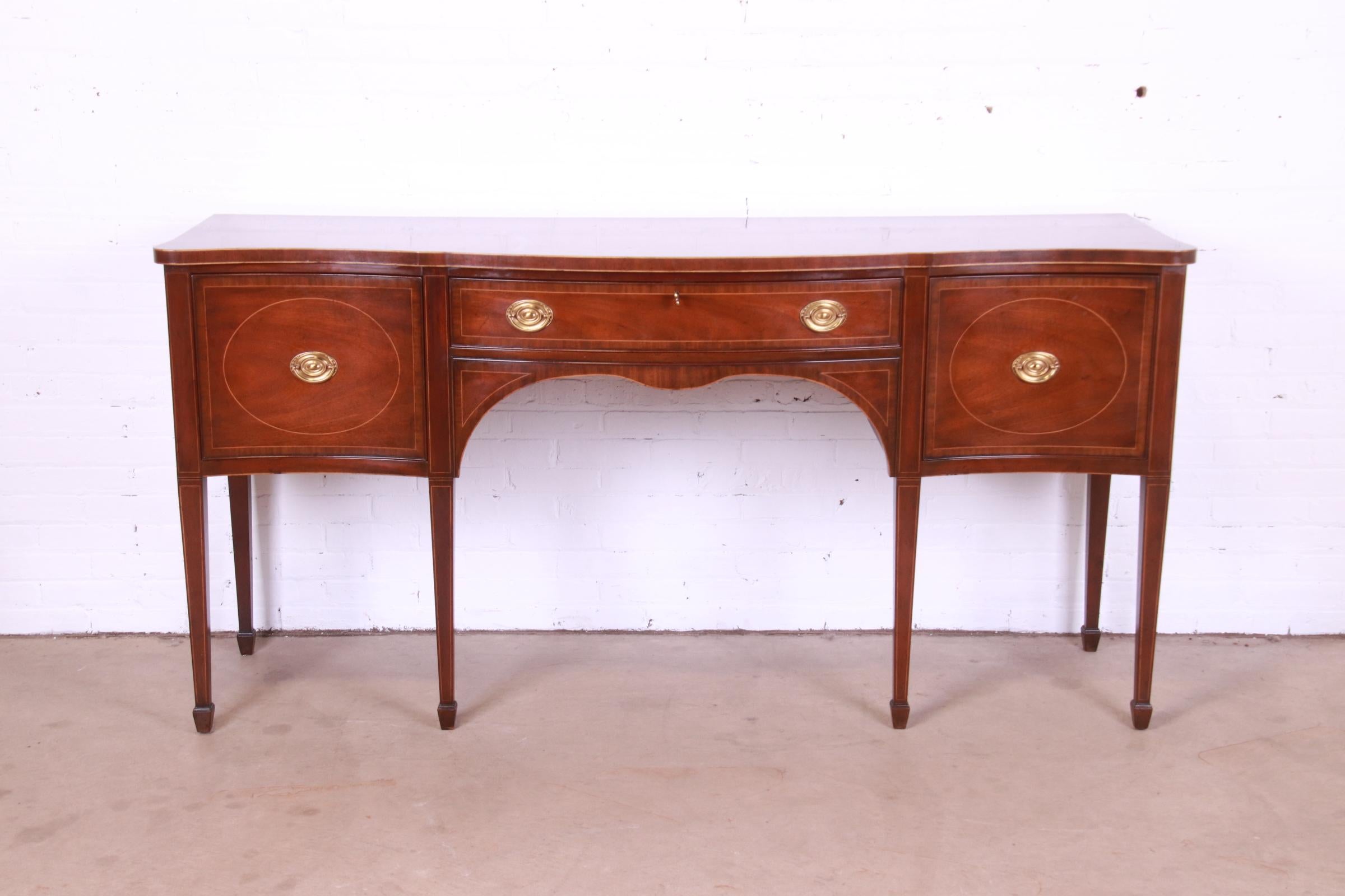 A gorgeous Federal or Hepplewhite style sideboard buffet or credenza

By Kittinger

USA, Circa 1980s

Mahogany, with satinwood inlay, and original brass hardware. Top drawer locks, and key is included.

Measures: 79