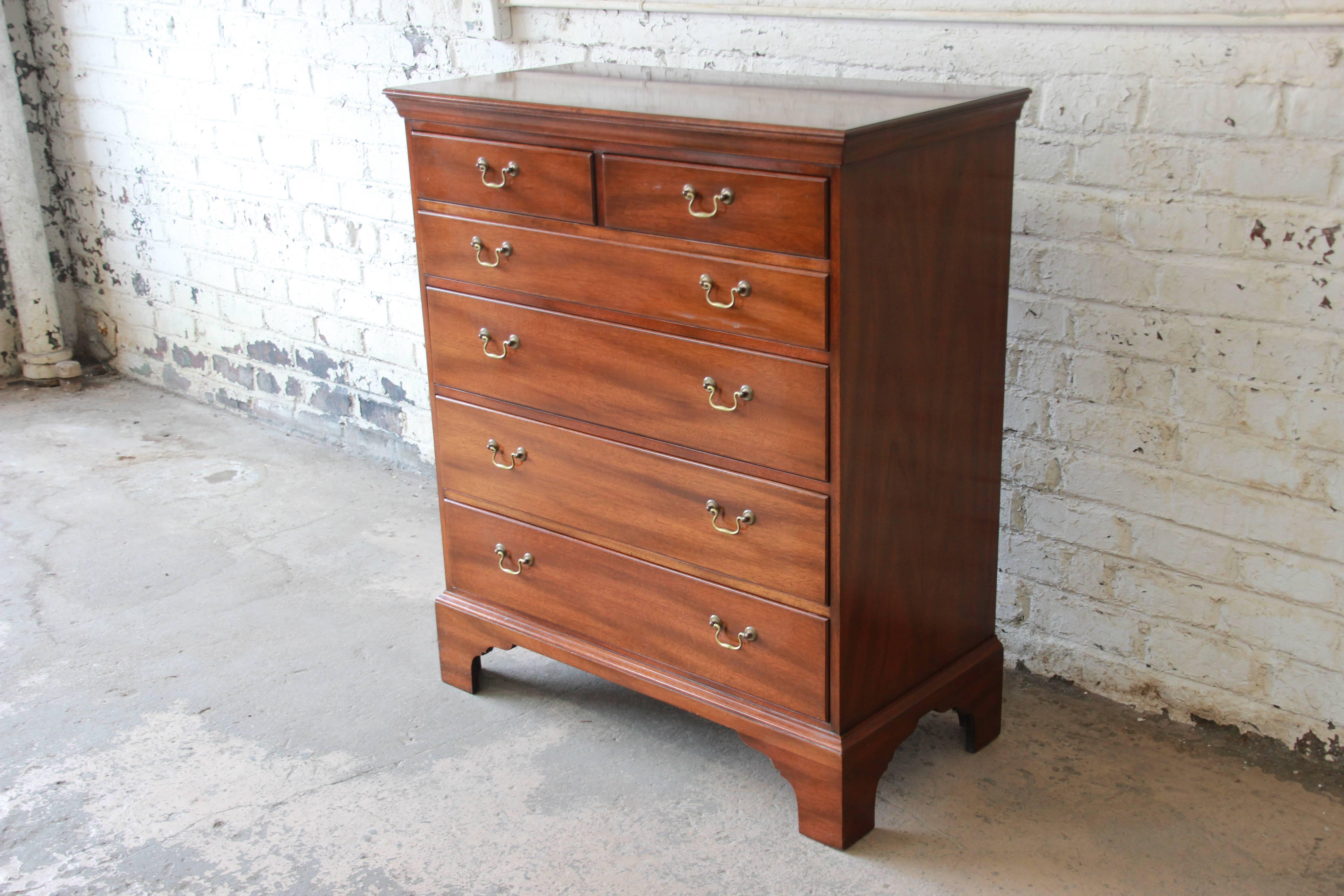 Offering a very nice and historic rendition Kittinger Williamsburg highboy dresser. This dresser has an elegant English design with six smooth sliding drawers for ample storage. It has a nice wood grain that appears to have a walnut graining on the