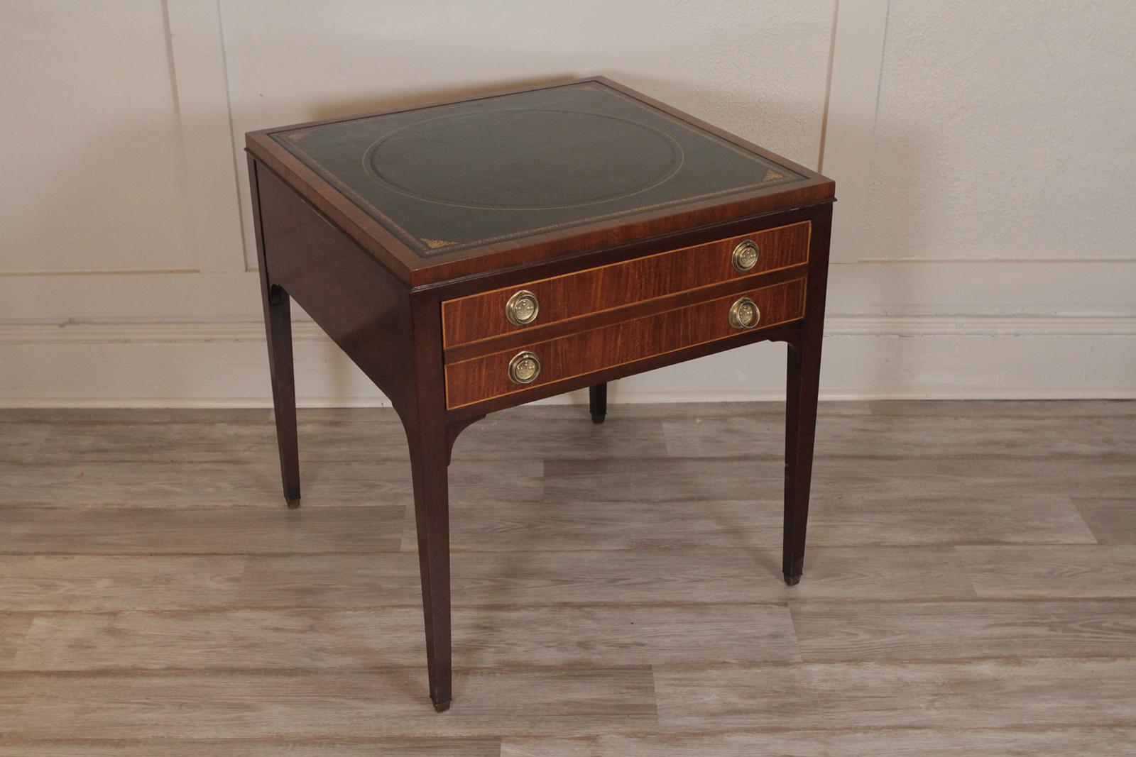 Kittinger leather top one drawer table. Elegant clean lines with hand gilt tooled dark green leather top. The drawer with polished brass Hepplewhite style handles. Dimensions: 26' W x 26” D x 27.5” H.