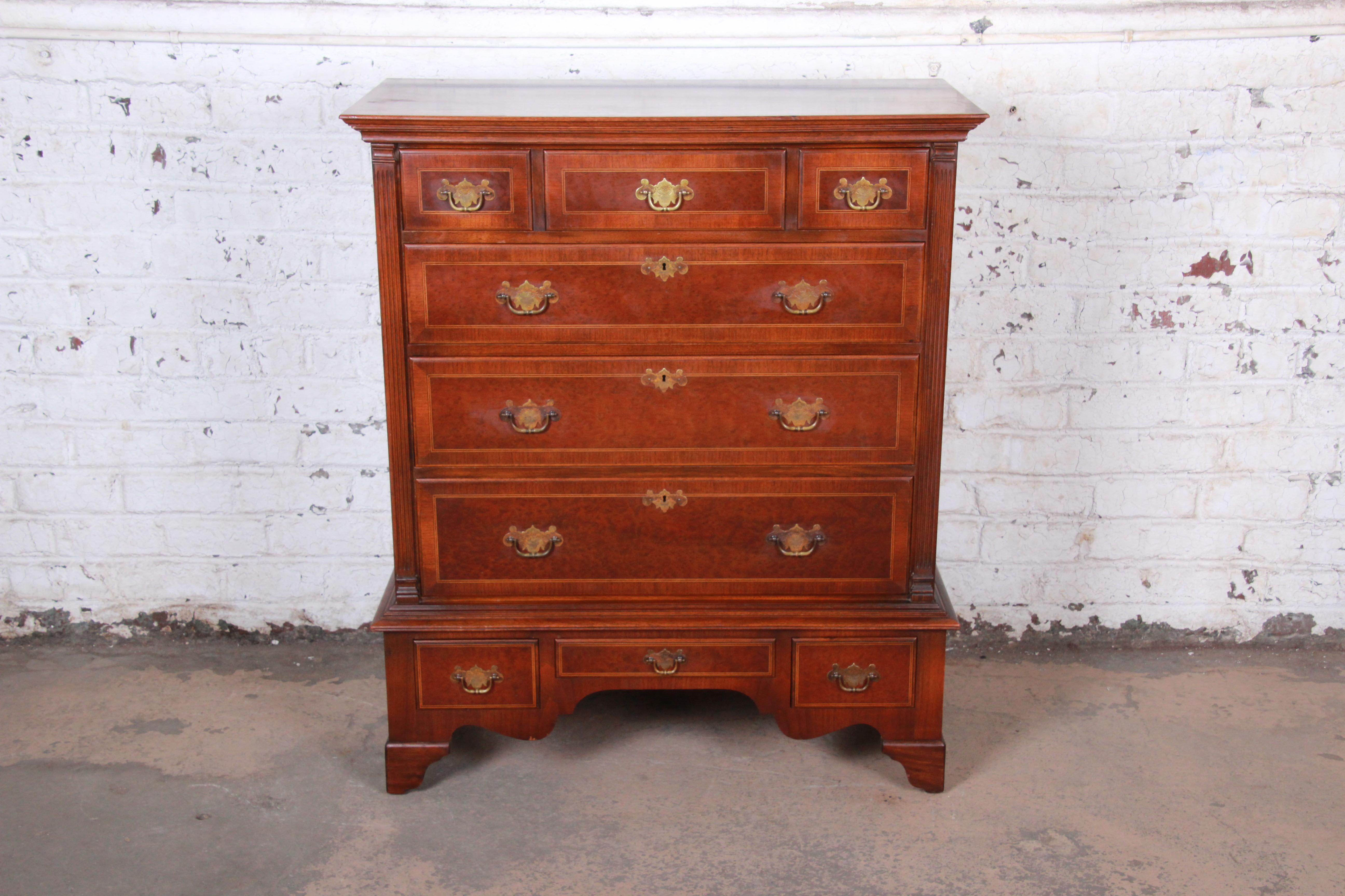 An exceptional mahogany and bird's-eye maple highboy chest of drawers by Kittinger Furniture. The dresser features gorgeous mahogany wood grain with inlaid bird's-eye maple drawer fronts. It offers excellent storage, with nine dovetailed drawers.