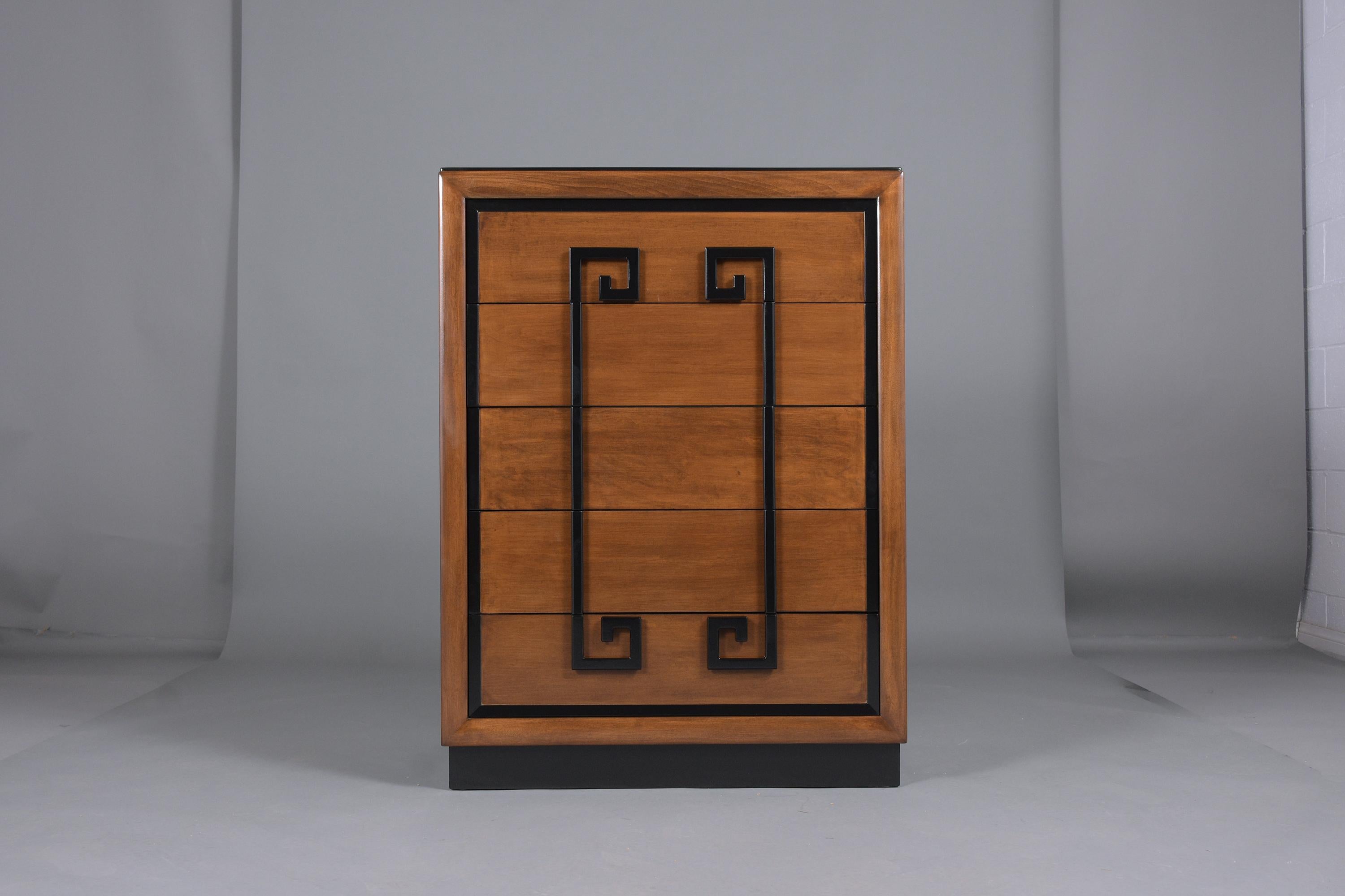 This tall chest by Kittinger is in great condition, features greek key handles, and is finished in mahogany and ebonized color with a lacquered finish. The dresser comes with five drawers that open and close with ease, offer plenty of storage space