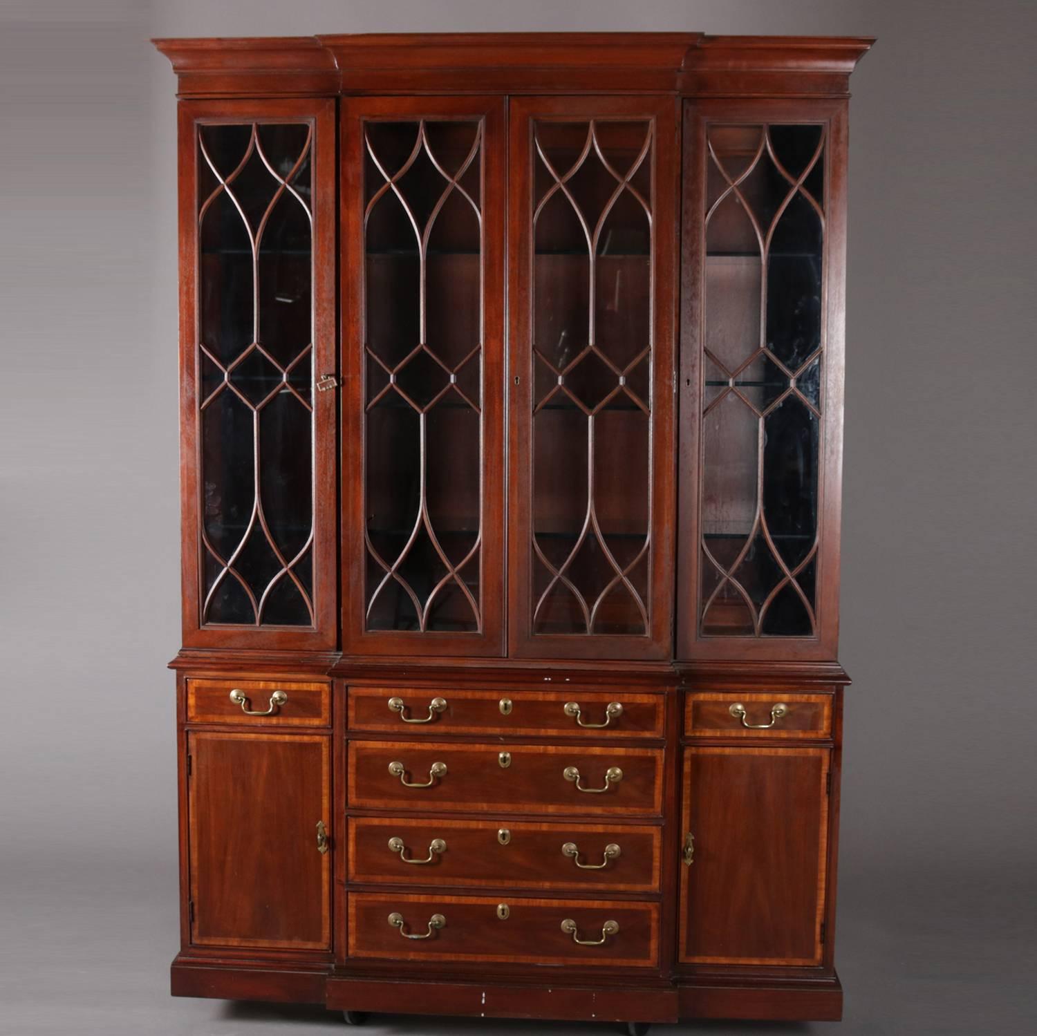 Kittinger school breakfront features mahogany construction with satinwood inlaid banding, four door upper china cabinet with adjustable shelves; lower with three upper drawers over three lower drawers with flanking side cabinets; locking and with