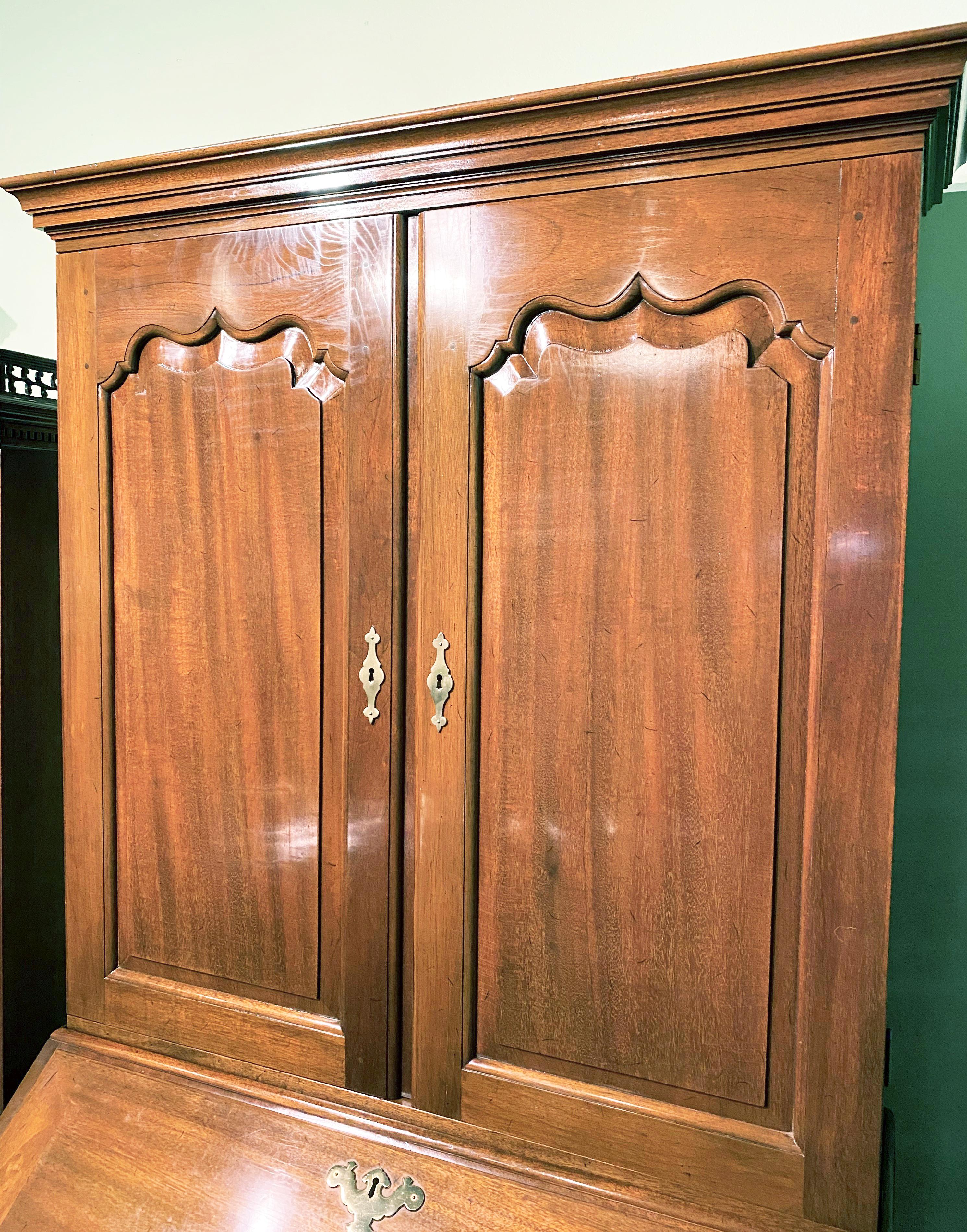 A fine example of a two piece mahogany blind door secretary desk / bookcase in the Chippendale style by Kittinger from their Williamsburg Adaptation collection, its upper case with a molded cornice surmounting two blind paneled doors, which opens to