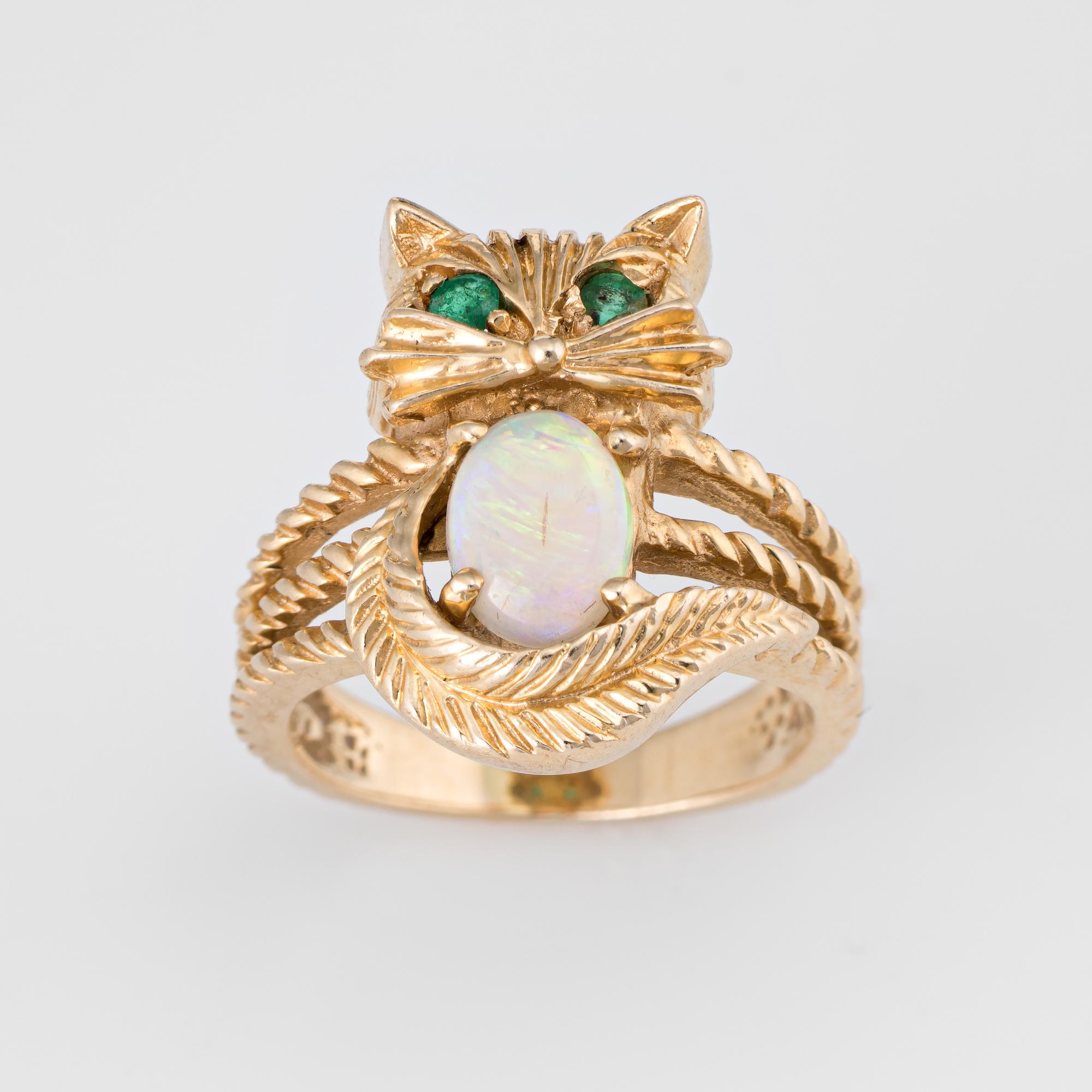 Stylish vintage opal & emerald kitty cat ring crafted in 14 karat yellow gold. 

Cabochon cut natural opal measures 7mm x 5mm (estimated at 1 carat), accented with 2 estimated 0.01 carat emeralds (estimated at .02 carats). The opal is in excellent