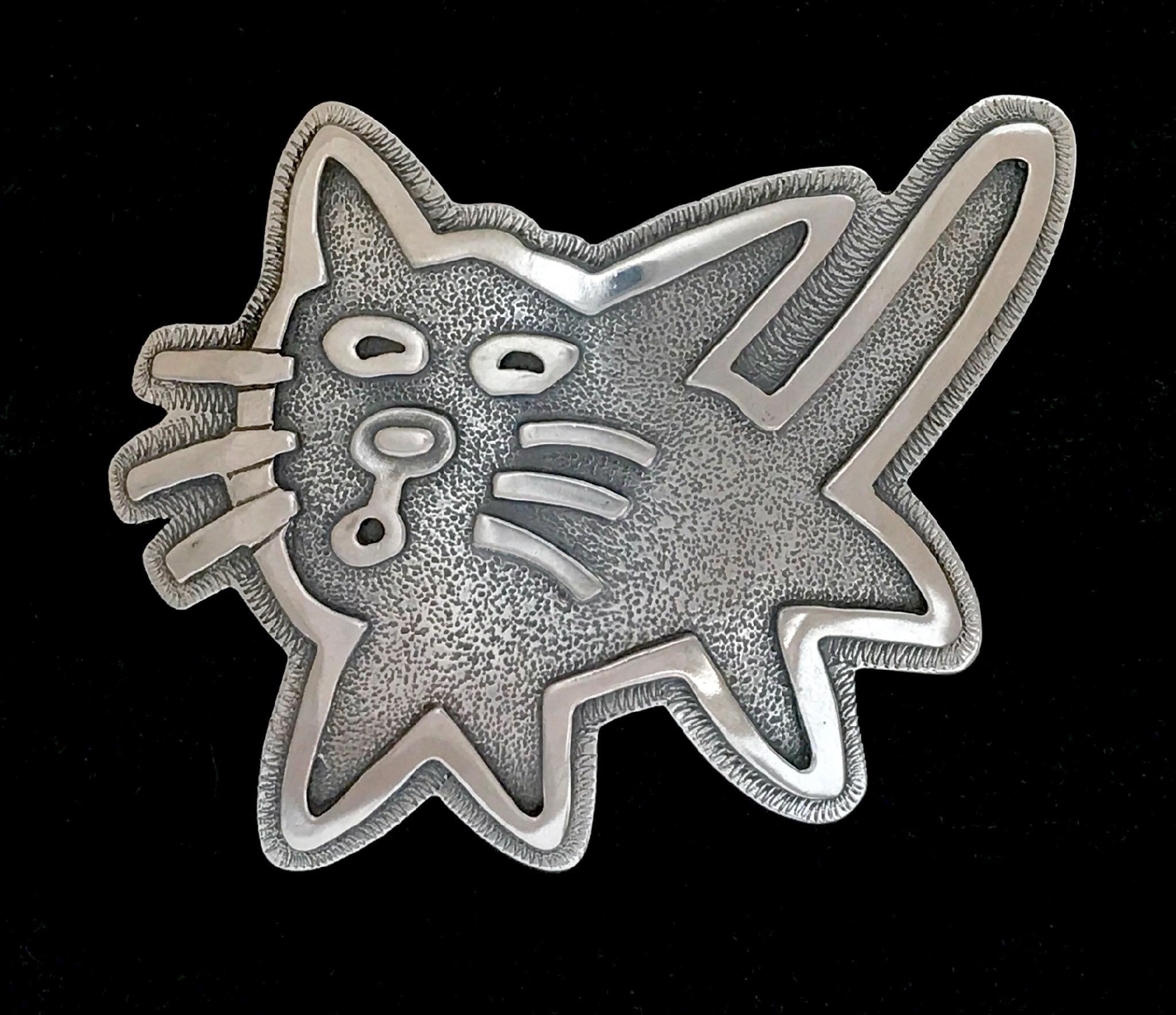 Kitty, ciondolo medio, di Melanie Yazzie, Navajo, Indigeno, argento, gatto

Melanie A. Yazzie (Navajo-Diné) è un'artista multimediale molto apprezzata, conosciuta per le sue stampe, i suoi dipinti, le sue sculture e i suoi design di gioielli. Ha