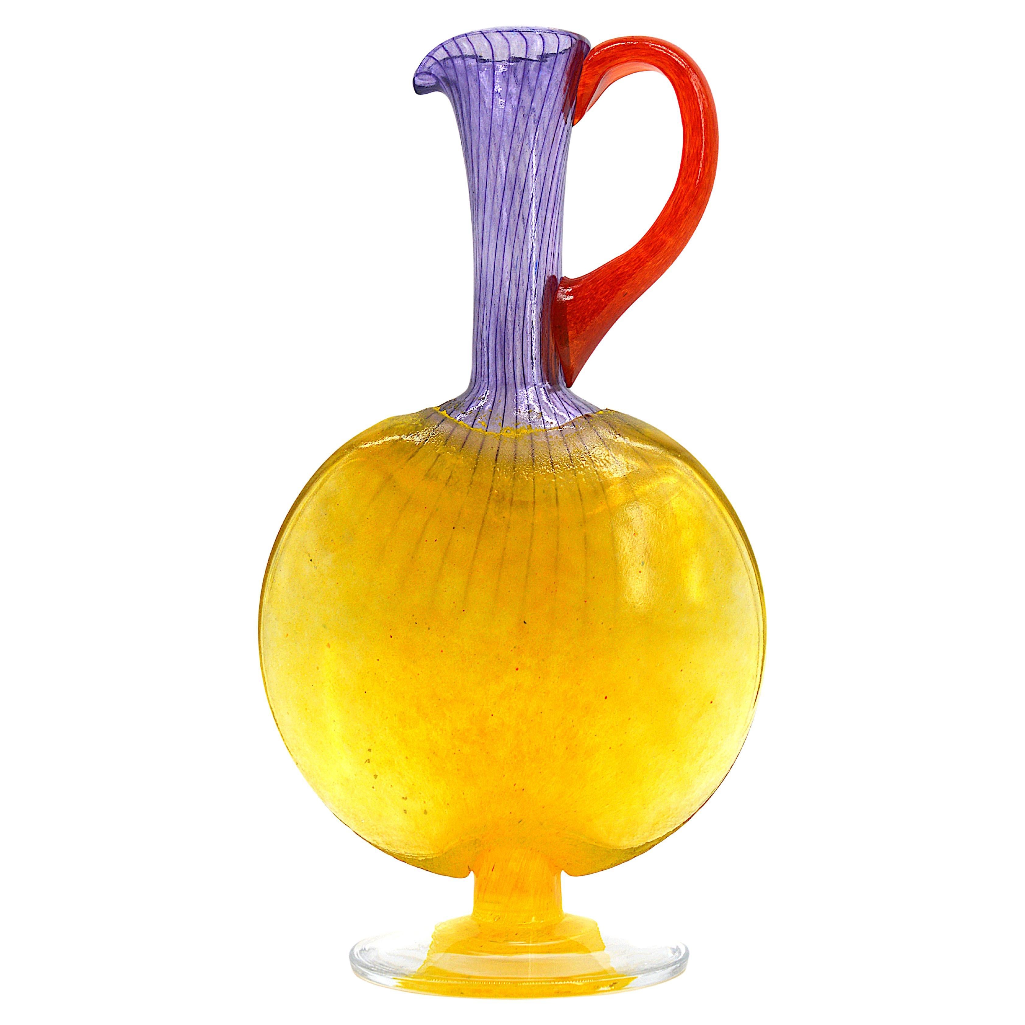 Caraffa in vetro artistico di Kjell Engman presso Kosta Boda, Svezia, fine anni '90. Vetro filigranato con base e corpo gialli, collo viola e manico rosso. Misure: Altezza 9,5