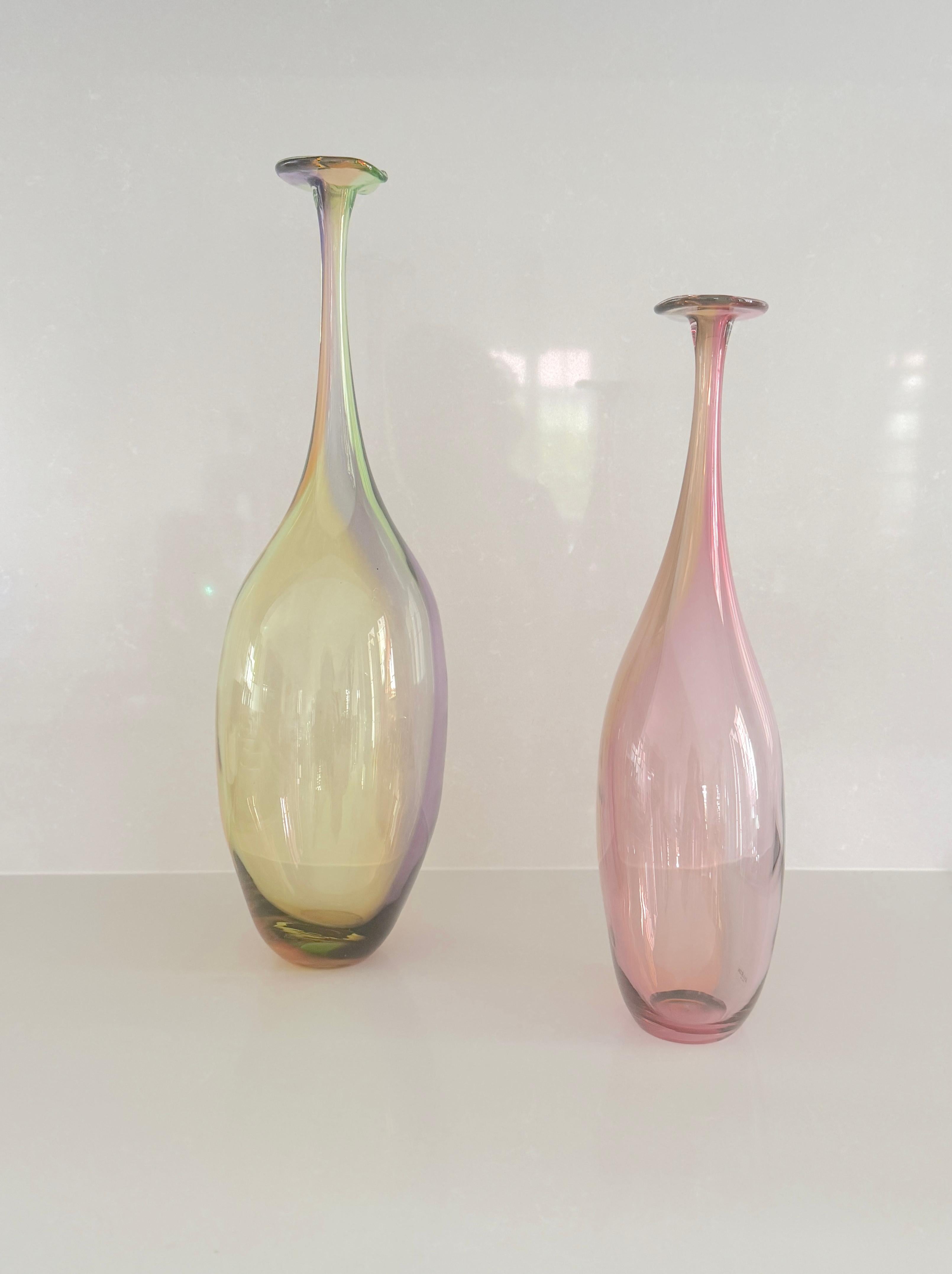 Coppia di bottiglie dai colori caldi con forme arrotondate e colli lunghi e fieri. Sono necessarie grandi abilità da parte degli artigiani per creare le combinazioni di colori uniche e le forme dolcemente arrotondate di queste affascinanti