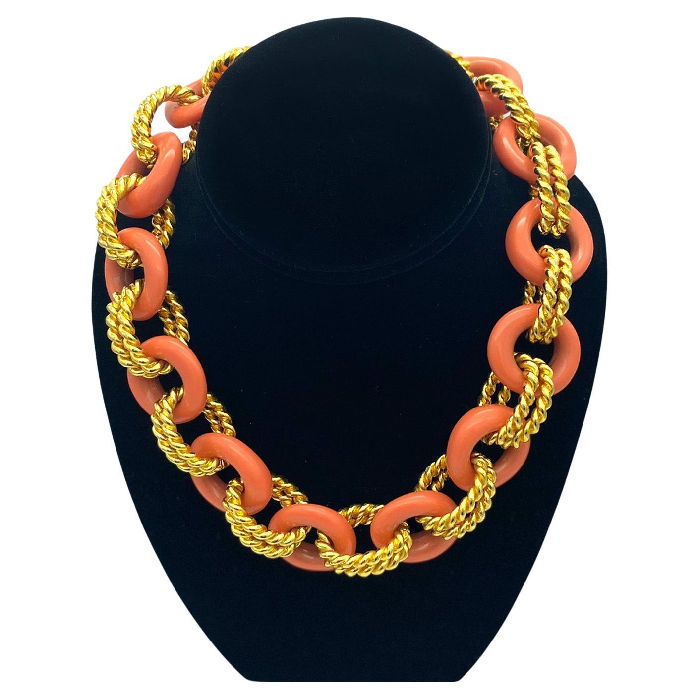 Dies ist ein Kenneth Jay Lane Vintage Koralle und Gold klobig Link Halskette. Zwölf korallenfarbene Harz-Donuts sind mit doppelten goldfarbenen, gedrehten Ringen verbunden. Auf dem Knebelverschluss ist KJL eingeprägt. Diese 17-Zoll-Halskette passt