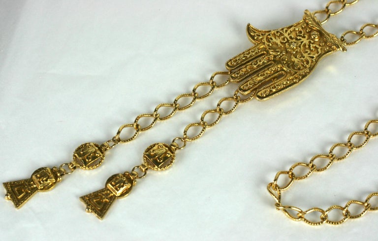 K.J.L Hamsa Necklace/Belt in gilt metal with adjustable chain and gilt tassels. Hamsa symbol is decorated with ornate filigree designs. Signed KJL. 
Excellent condition.
46