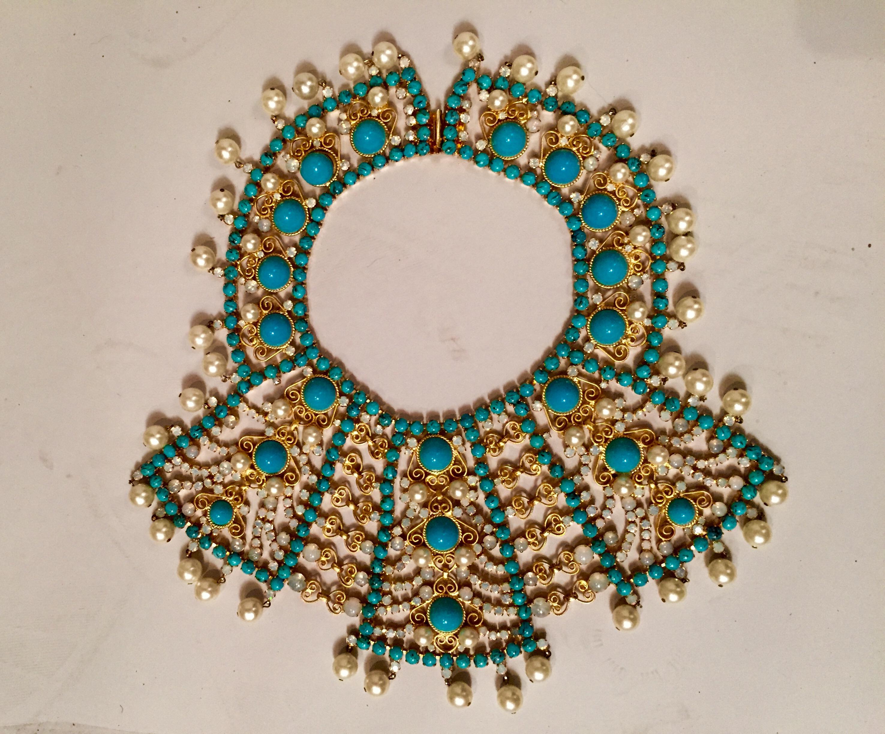 A striking combination of large and small turquoise stones, cabochon and faceted moonstones in two sizes and lustrous pearls that are set into the necklace as well as suspended along the edge. This large scale bib necklace is made from gold toned