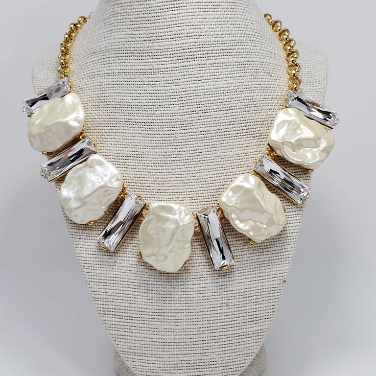 A faux mother of pearl and clear emerald-cut crystal collar necklace by Kenneth Jay Lane. Gold-plated chain.

Hallmarks: Kenneth Lane, Made in USA
43 cm length + 10 cm extension