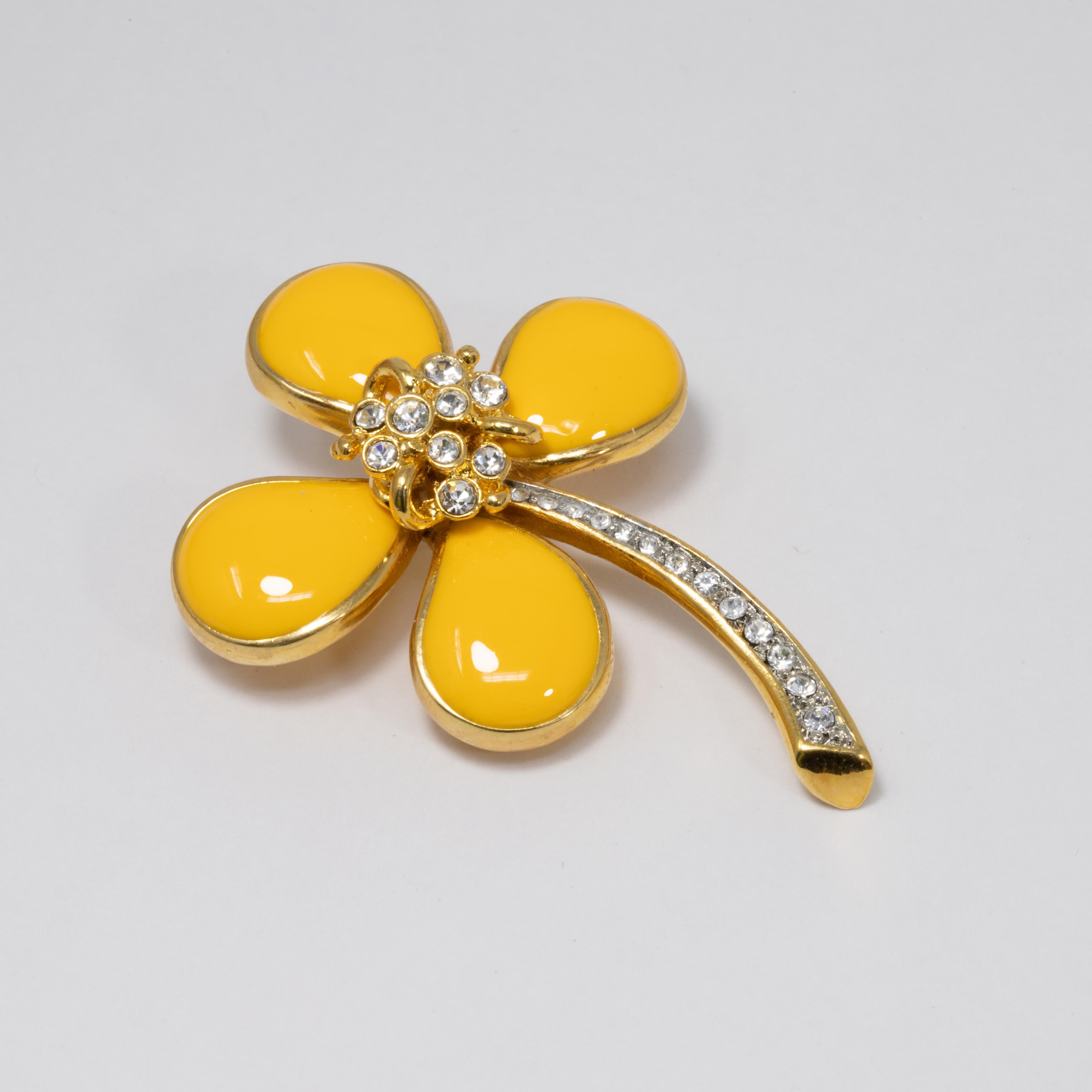 An embellished flower pin brooch by Kenneth Jay Lane. Features vibrant yellow petals accented with a clear crystal center and gold-plated stem.

Hallmarks: Kenneth Lane, Made in USA