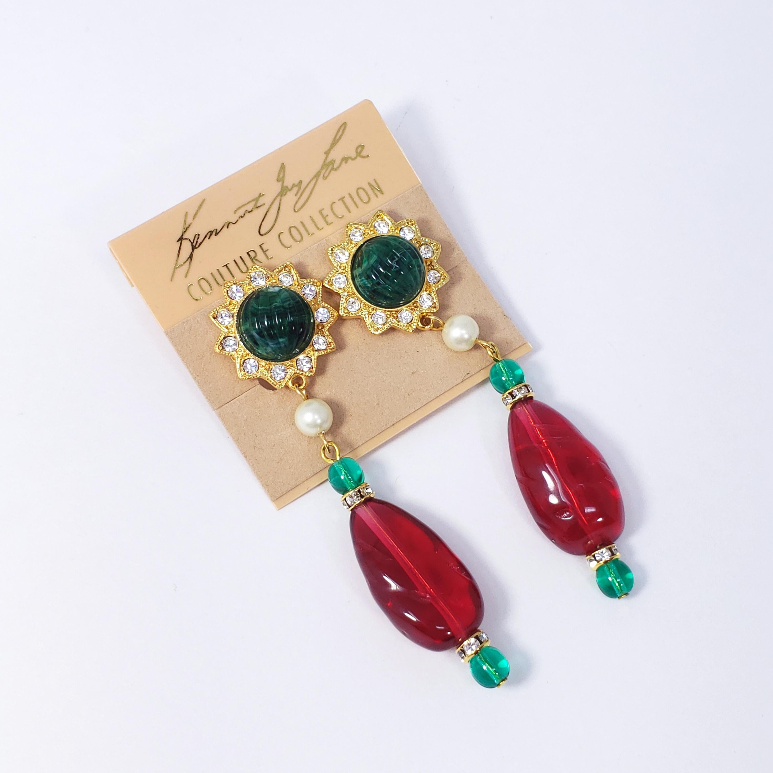 A pair of dangling clip on earrings by Kenneth Jay Lane. Each features carved ruby and emerald-colored resin accents decorated with clear crystals and a single faux pearl. A perfect touch of color!

Hallmarks: Kenneth © Lane, Made in USA