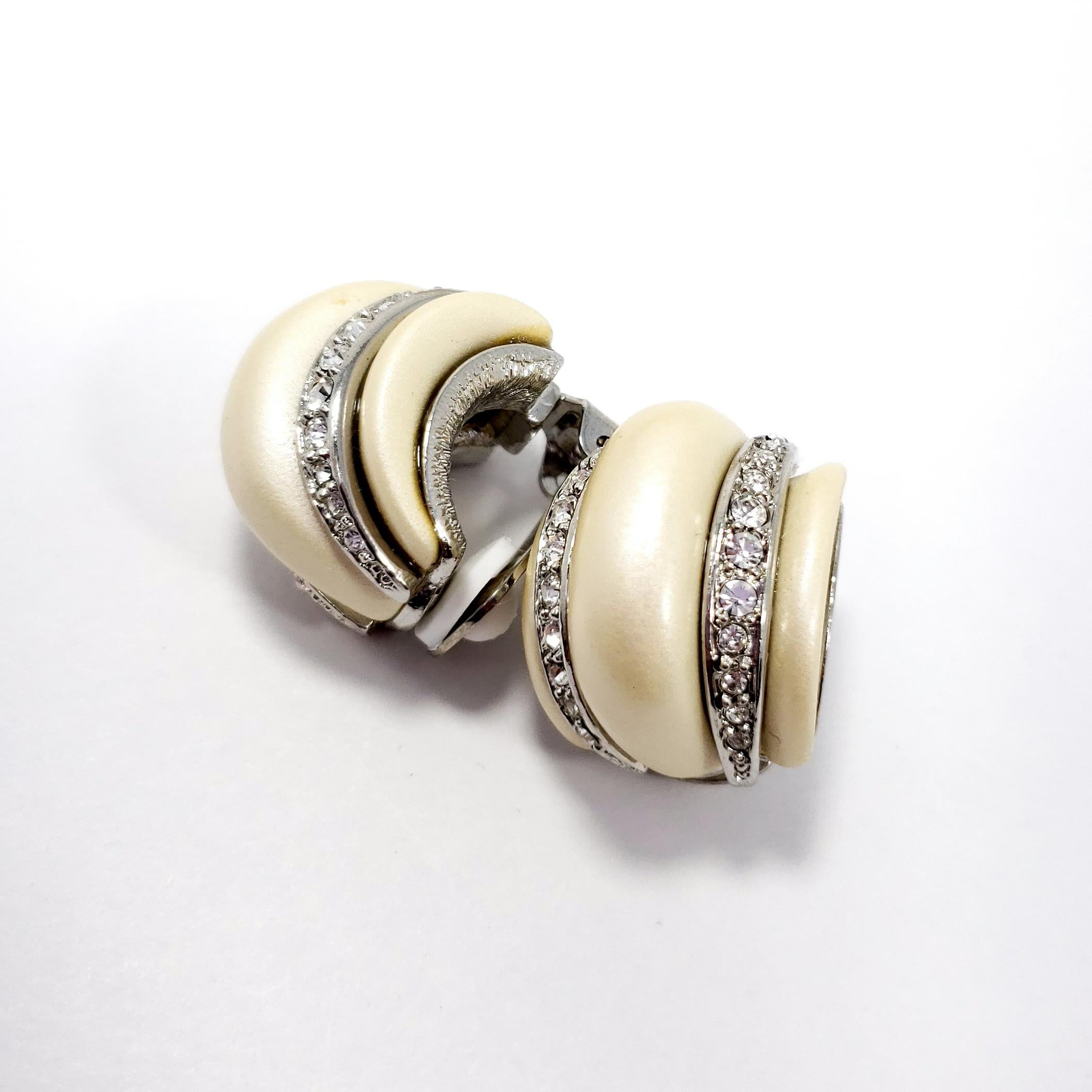 Stylish silver clip on earrings from Kenneth Jay Lane. Each earring features faux mother of pearl decorated with clear crystals. 

Hallmarks: KJL