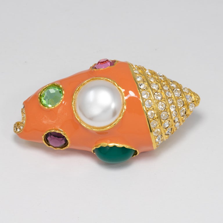 A unique nautical-themed pin/brooch by KJL. Features A faux pearl, colorful cabochons, and crystals, set in gold-plated bezels. Painted coral enamel.

Kenneth Jay Lane.

Hallmarks: Kenneth © Lane, Made in USA