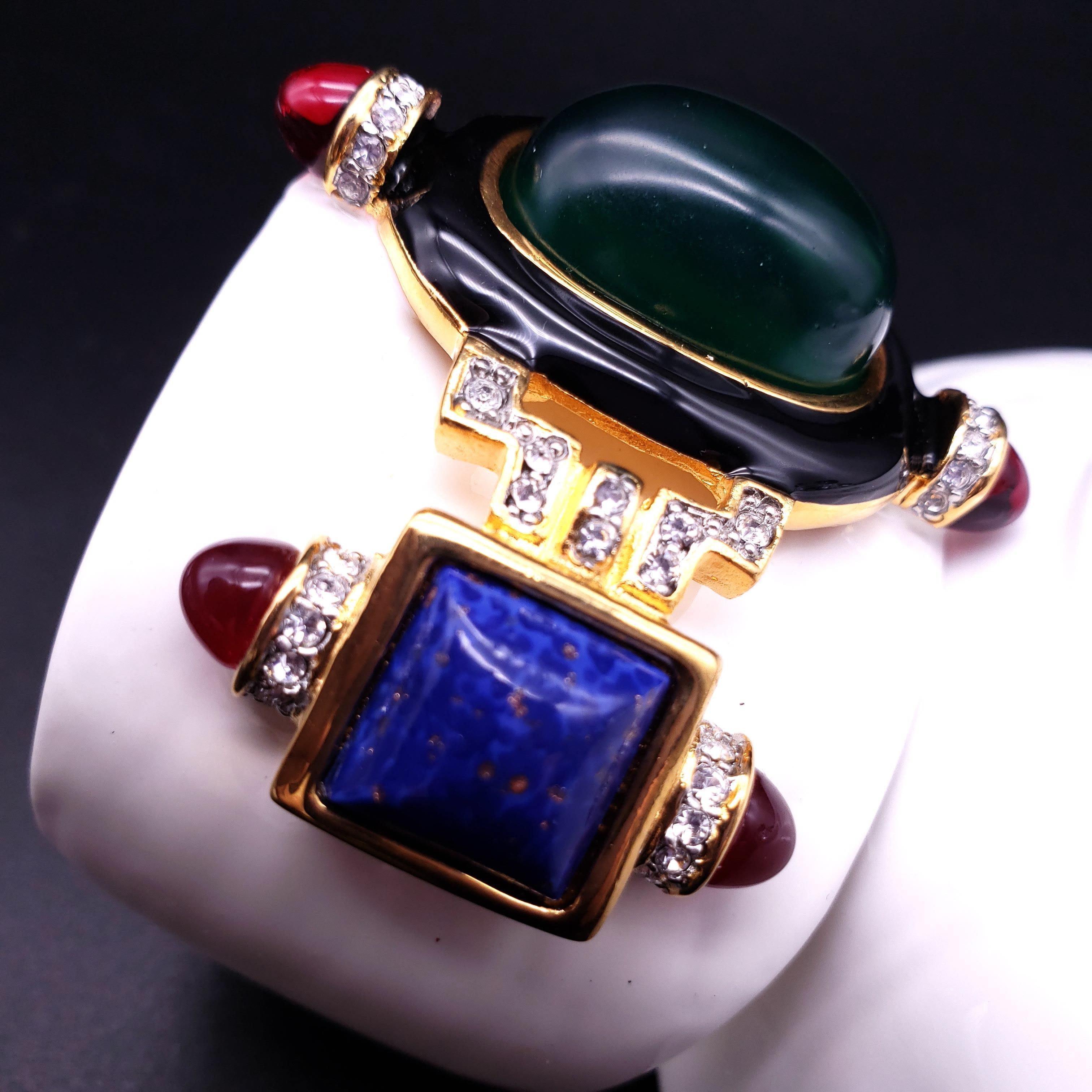 Kenneth Jay Lane cuff bracelet. White enamel and 22KT gold plated. Green resin cabochon centerpiece accented with faux emerald, lapis lazuli, and clear crystals.

...

Measurements: inner circumference 6