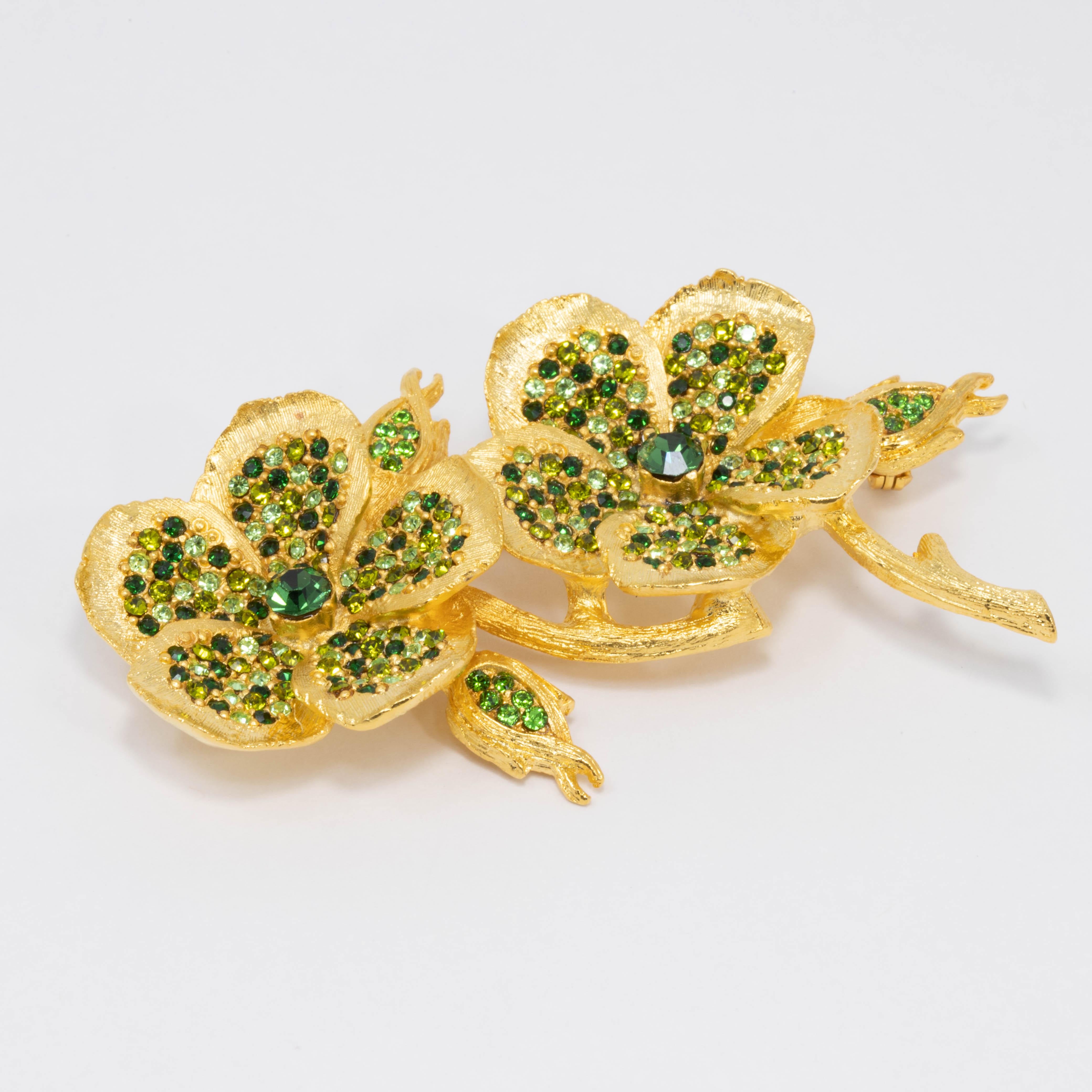 Mesmerizing green crystal centers surrounded by mini rhinestones in shades of green give this golden pin brooch a luxurious, verdant look.

Gold plated. By Kenneth Jay Lane. 

Tags, Marks, Hallmarks: Kenneth © Lane, Made in USA