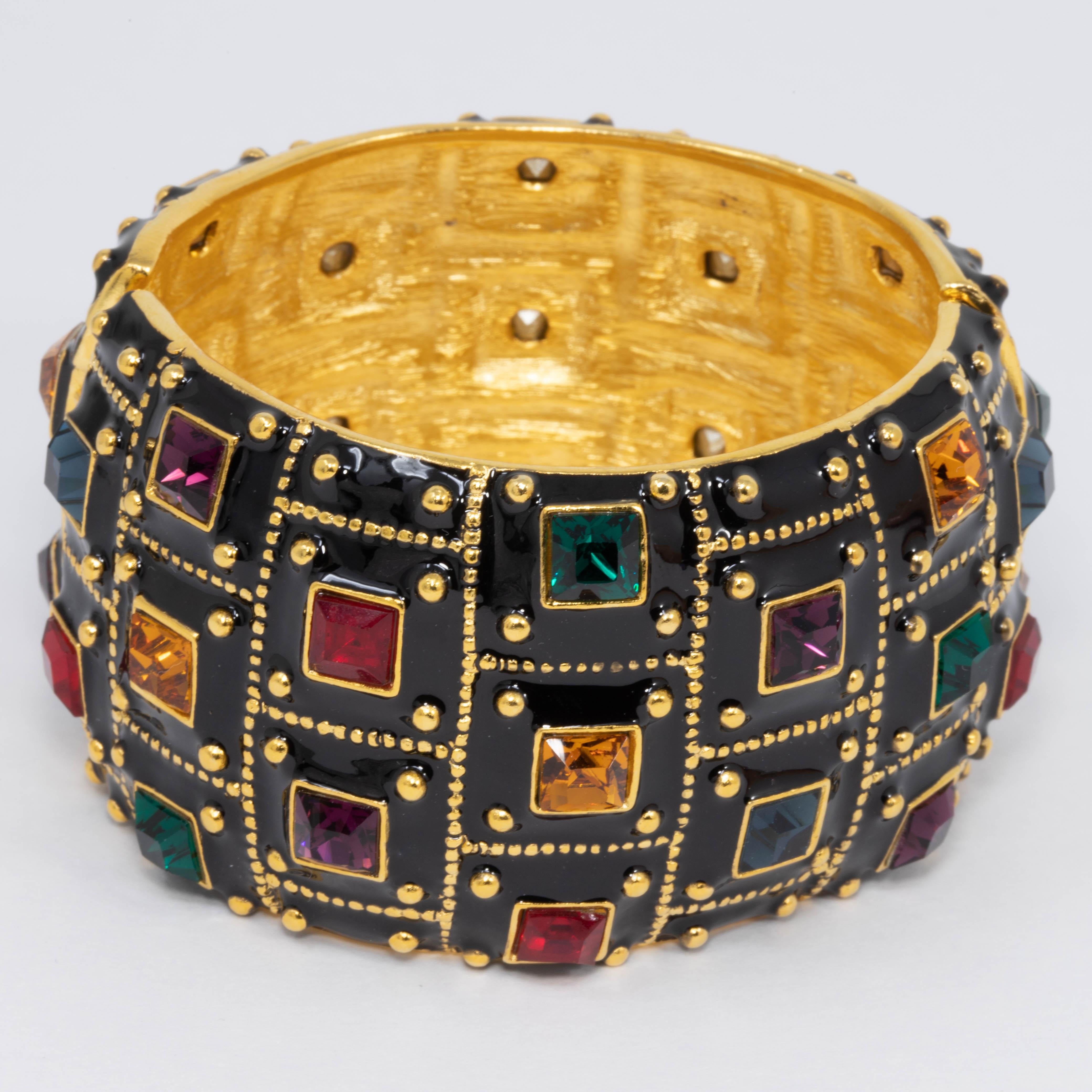 Exquisite jeweled bracelet by Kenneth Jay Lane. This gold-plated cuff featured painted black enamel, decorated with geometrical gold accents and colorful ruby, amethyst, amber, and emerald crystals.

Hinged bangle with magnetic closure.

Hallmarks: