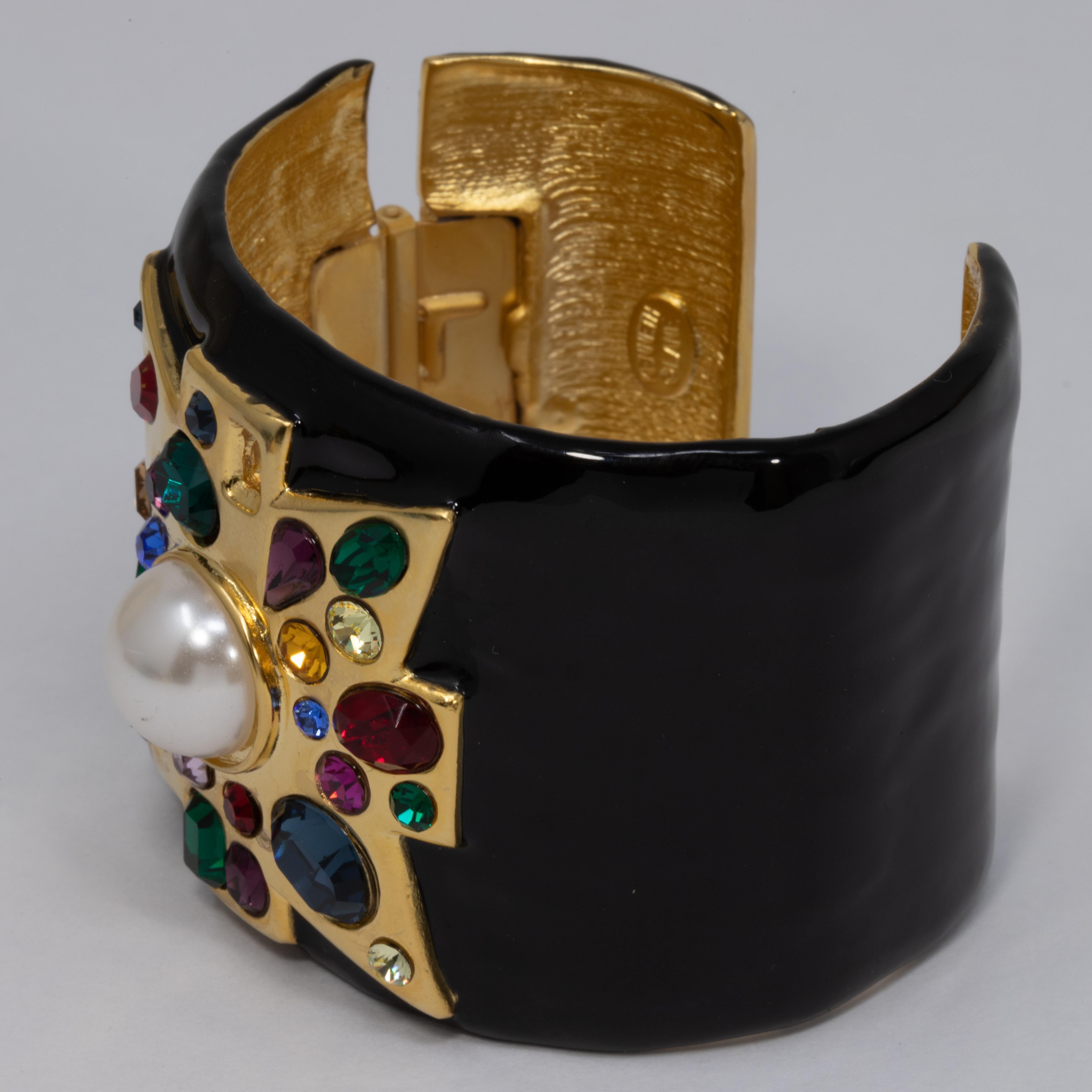 A stylish Kenneth Jay Lane cuff bracelet. Features a gold-plated tapered band painted in black enamel. A bold maltese cross motif is accented with colorful crystals and a vibrant centerpiece faux pearl.

Hallmarks: Kenneth Lane, Made in USA
Inner