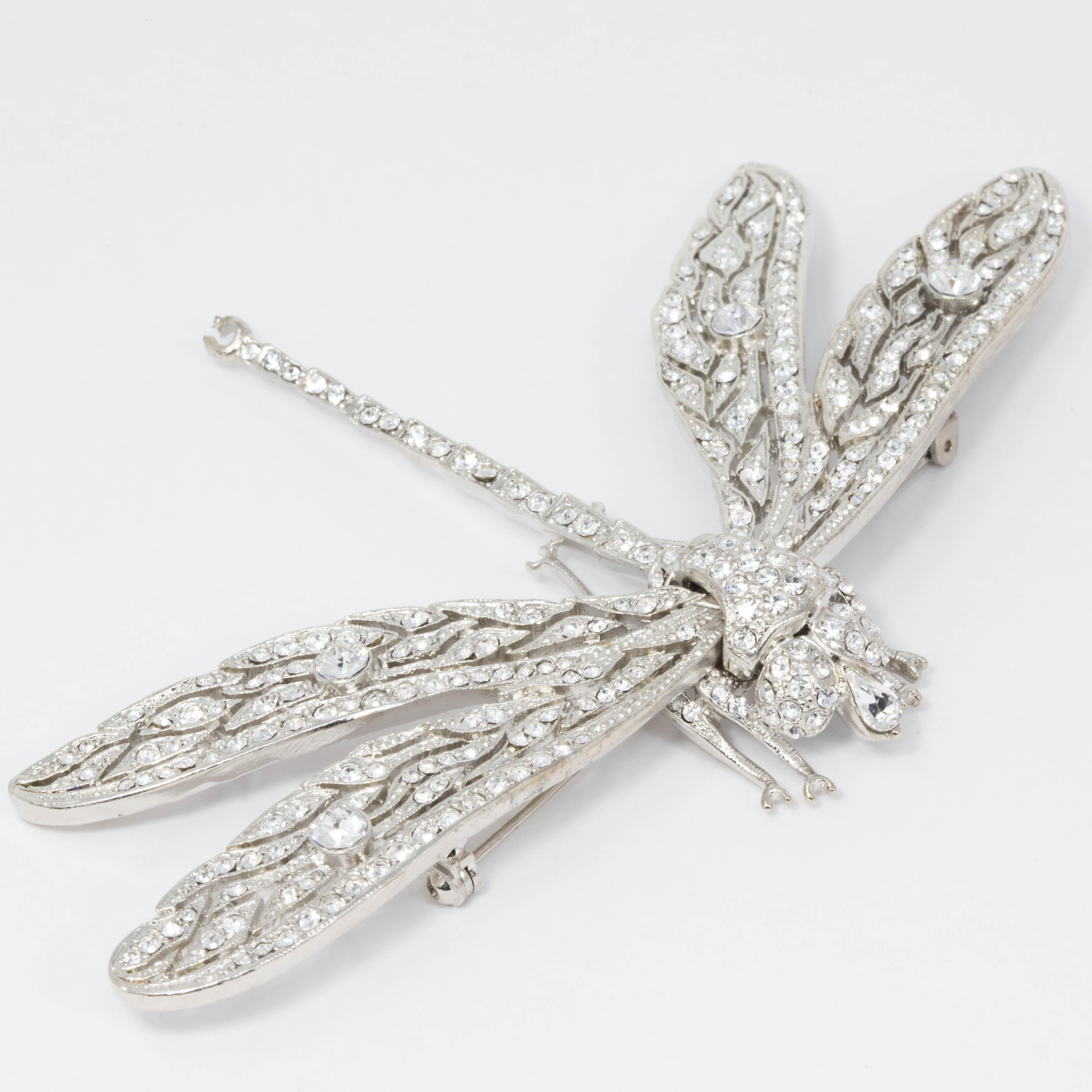 A glamorous silver dragonfly pin, decorated with sparkling clear crystals. Brooch by Kenneth Jay Lane.

Silver-tone.

Tags, Marks, Hallmarks: Kenneth © Lane