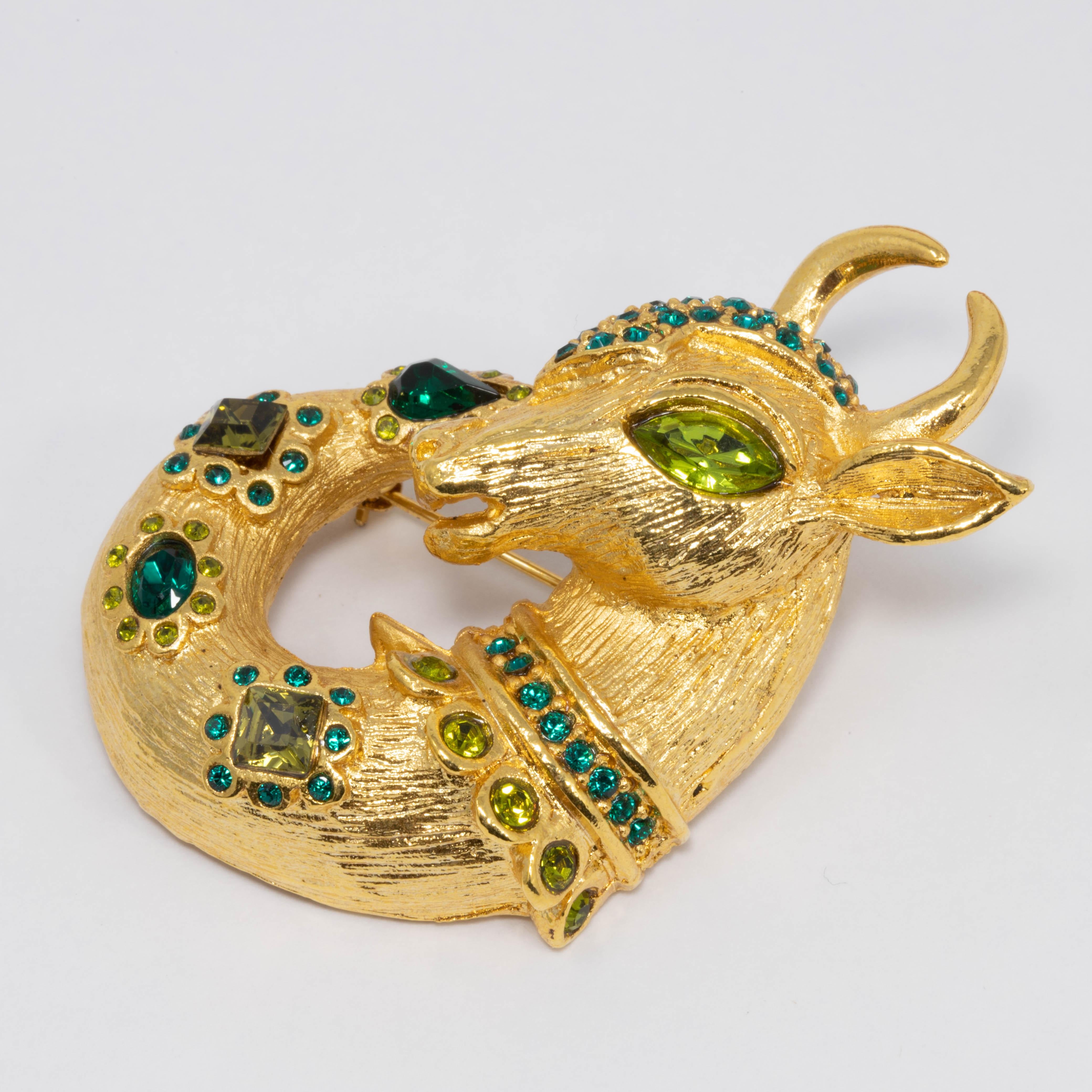 A golden mythological horned animal pin to add some magical allure to your style! Can be worn as a pin brooch or a necklace pendant. 

By Oscar de la Renta. Gold plated mythological deer / goat / ram motif. Green peridot and emerald colored