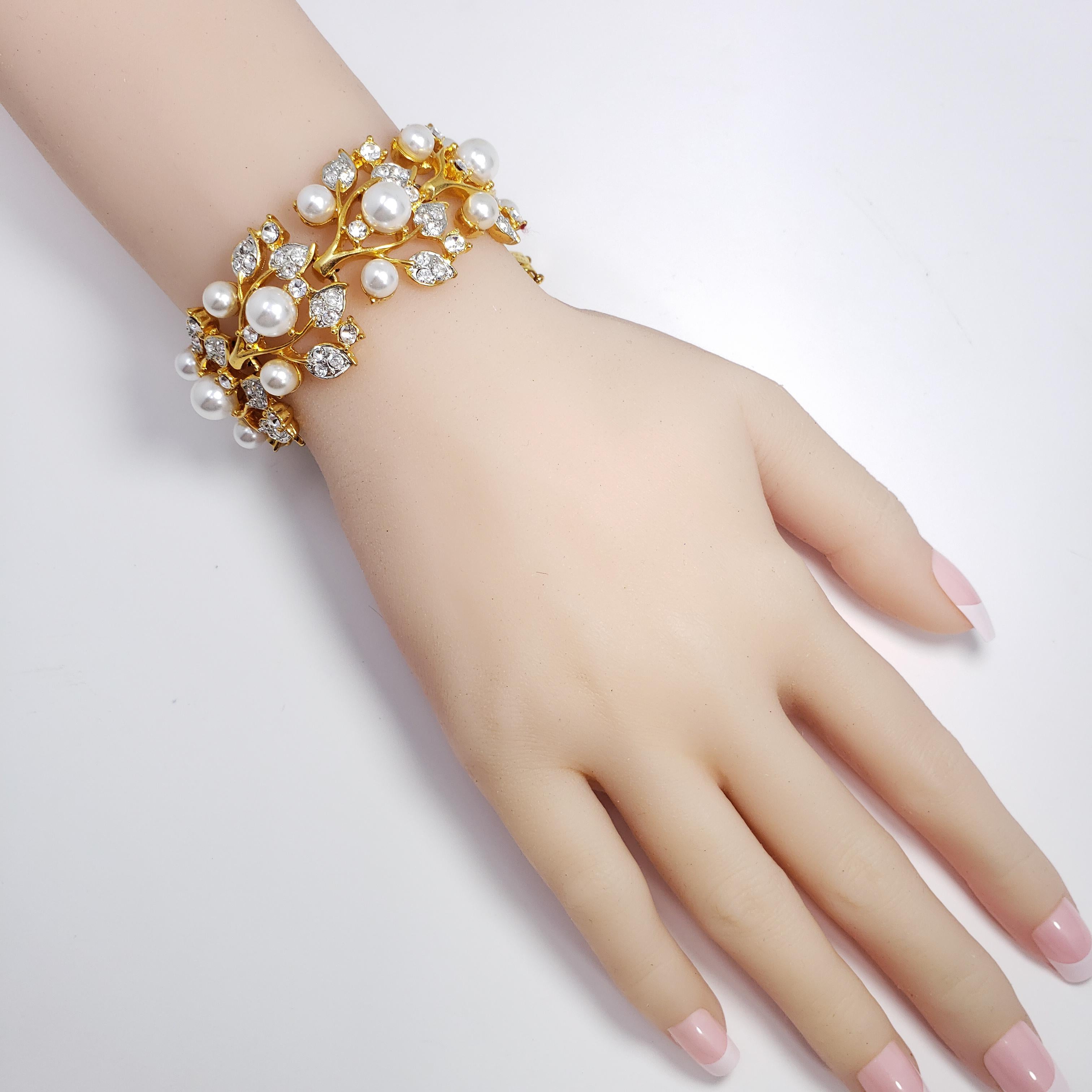 A stylish floral themed bracelet by Kenneth Jay Lane. This link bracelet features flowing, gold-tone leaf and branch motifs, accented with glass pearls and clear crystals. 

Hallmarks: Kenneth © Lane, Made in USA