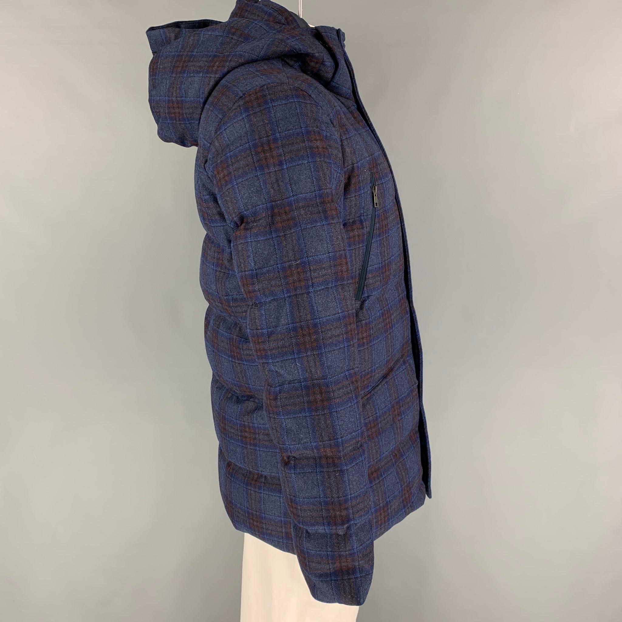 KJUS jacket comes in a navy & gray plaid quilted wool / cashmere fabric by Loro Piana featuring a hooded style, front pockets, sleeve logo detail, and a hidden zip & snap button closure. 

New With Tags. 
Marked: 52
Original Retail Price: