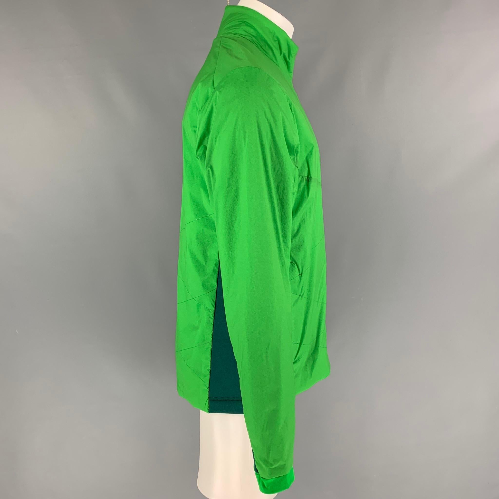 KJUS jacket comes in a green two toned nylon blend featuring a high collar, slit pockets, and a zip up closure. 

New With Tags. 
Marked: M

Measurements:

Shoulder: 19 in.
Chest: 42 in.
Sleeve: 28 in.
Length: 29 in. 
