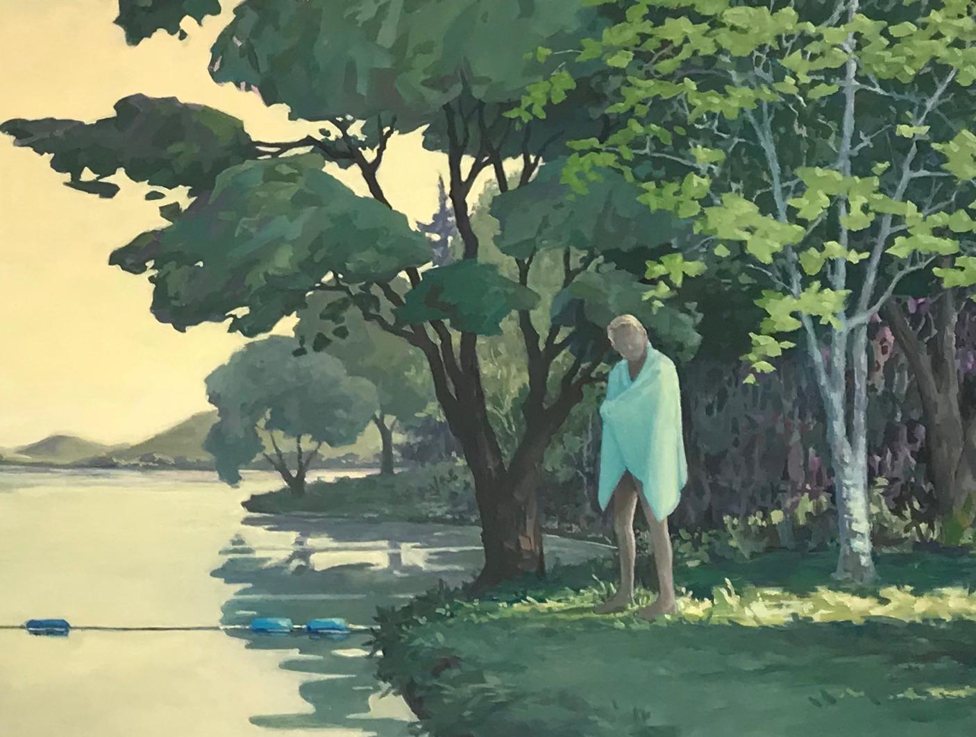 A tall, fair-haired figure wrapped in a light blue towel stands on the bank of inviting, calm water. Dark green trees in a forest, and mountains in the distance on the horizon reflect on the water's rippling surface in this peaceful landscape